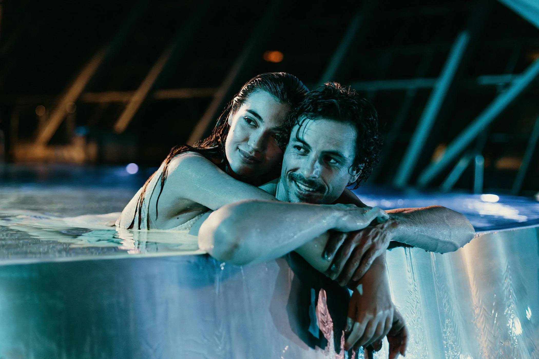 Una pareja en una piscina al atardecer, disfrutando juntos en agua.