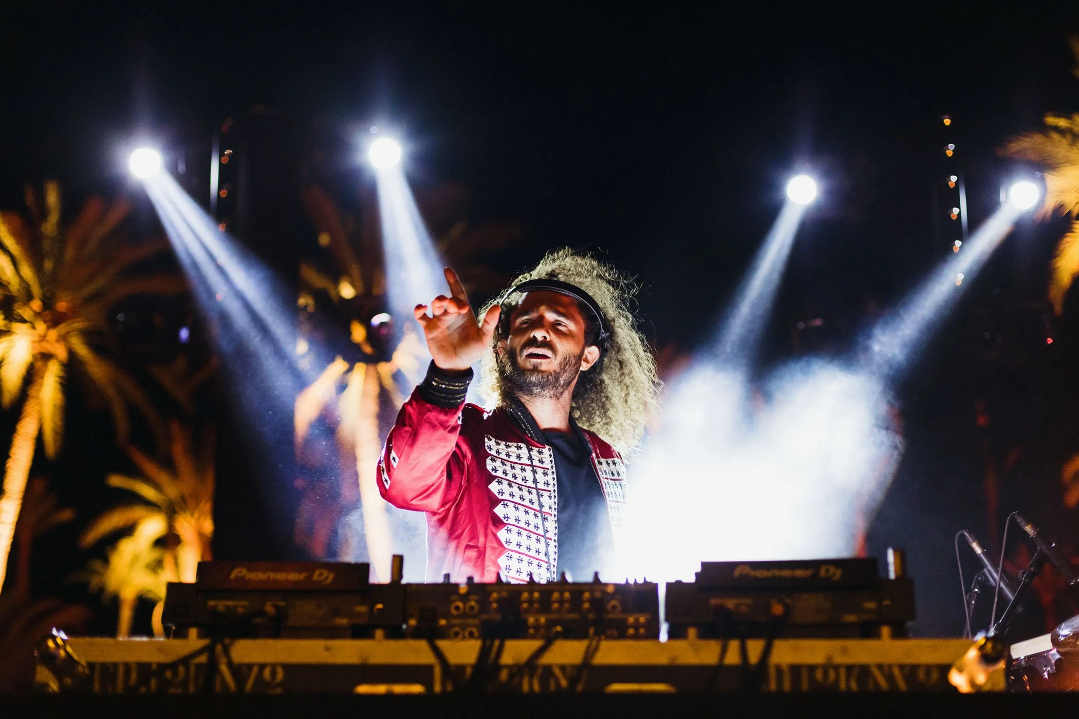 DJ con auriculares en un escenario con luces brillantes en la noche.
