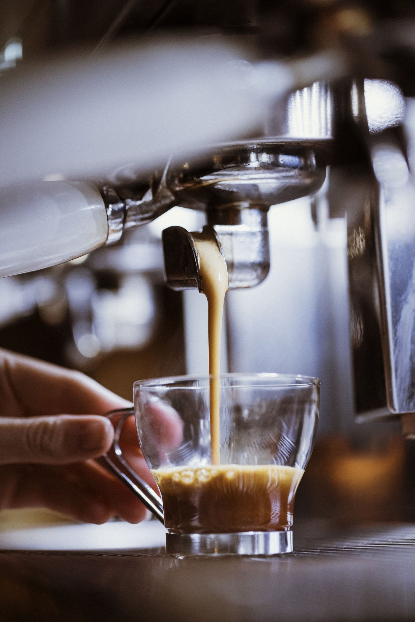 Maquina de espresso sirviendo café en una taza de vidrio.