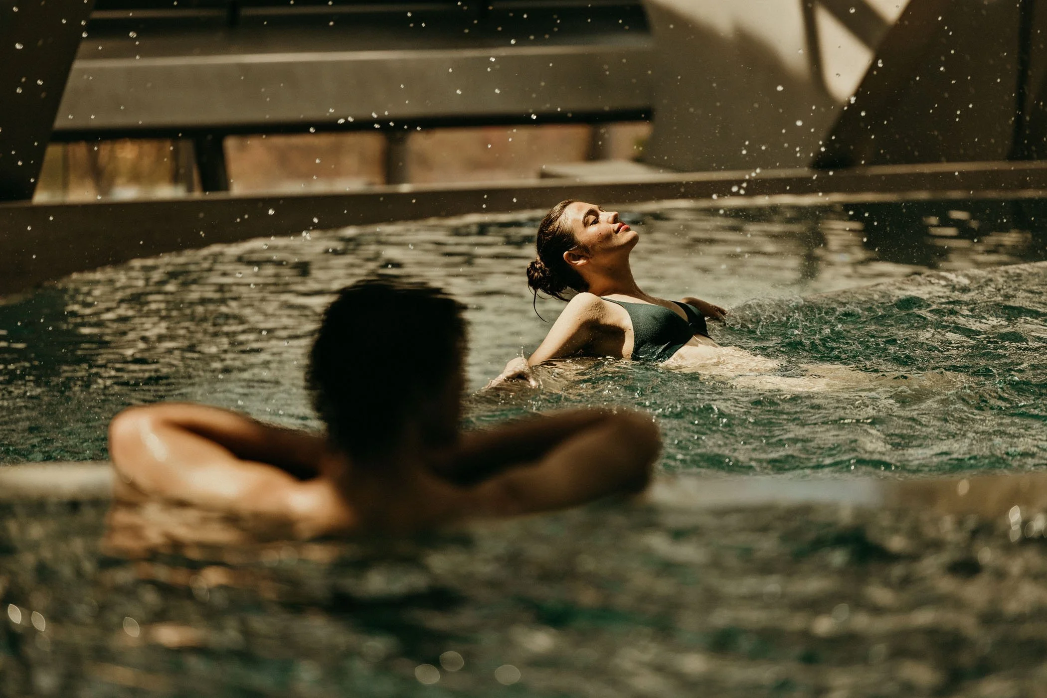 Una mujer disfrutando una sesión de spa en una piscina, con ojos cerrados y expresión de relajación.