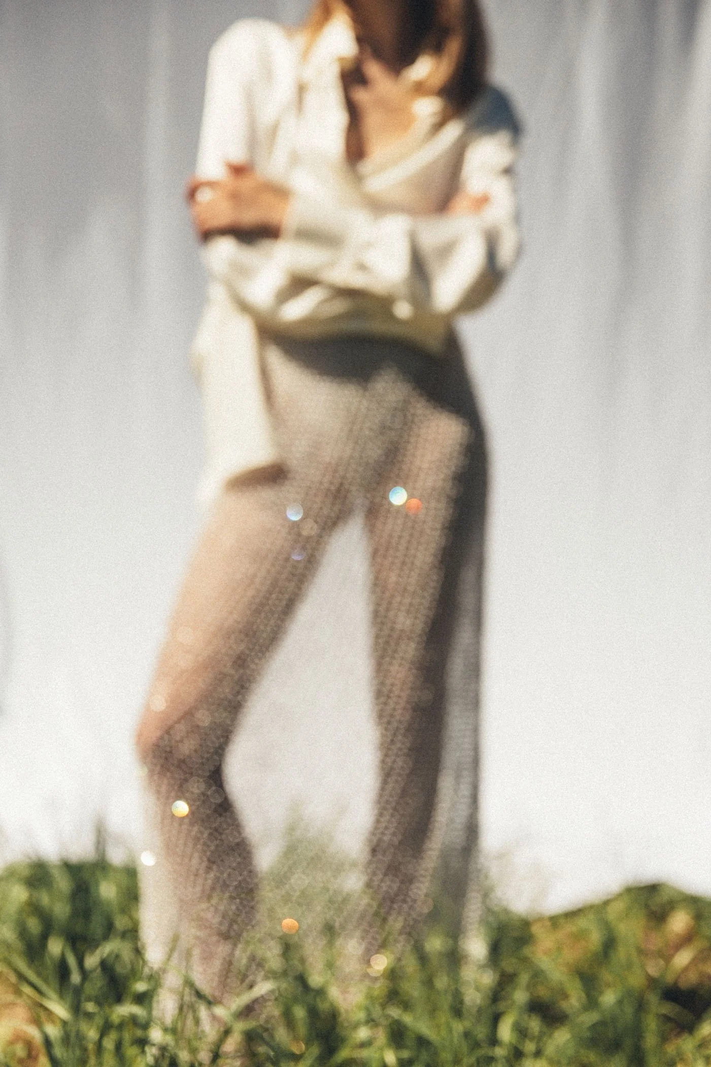 Persona con ropa clara y pantalones de malla de lentejuelas, posando al aire libre con fondo de césped y cielo.