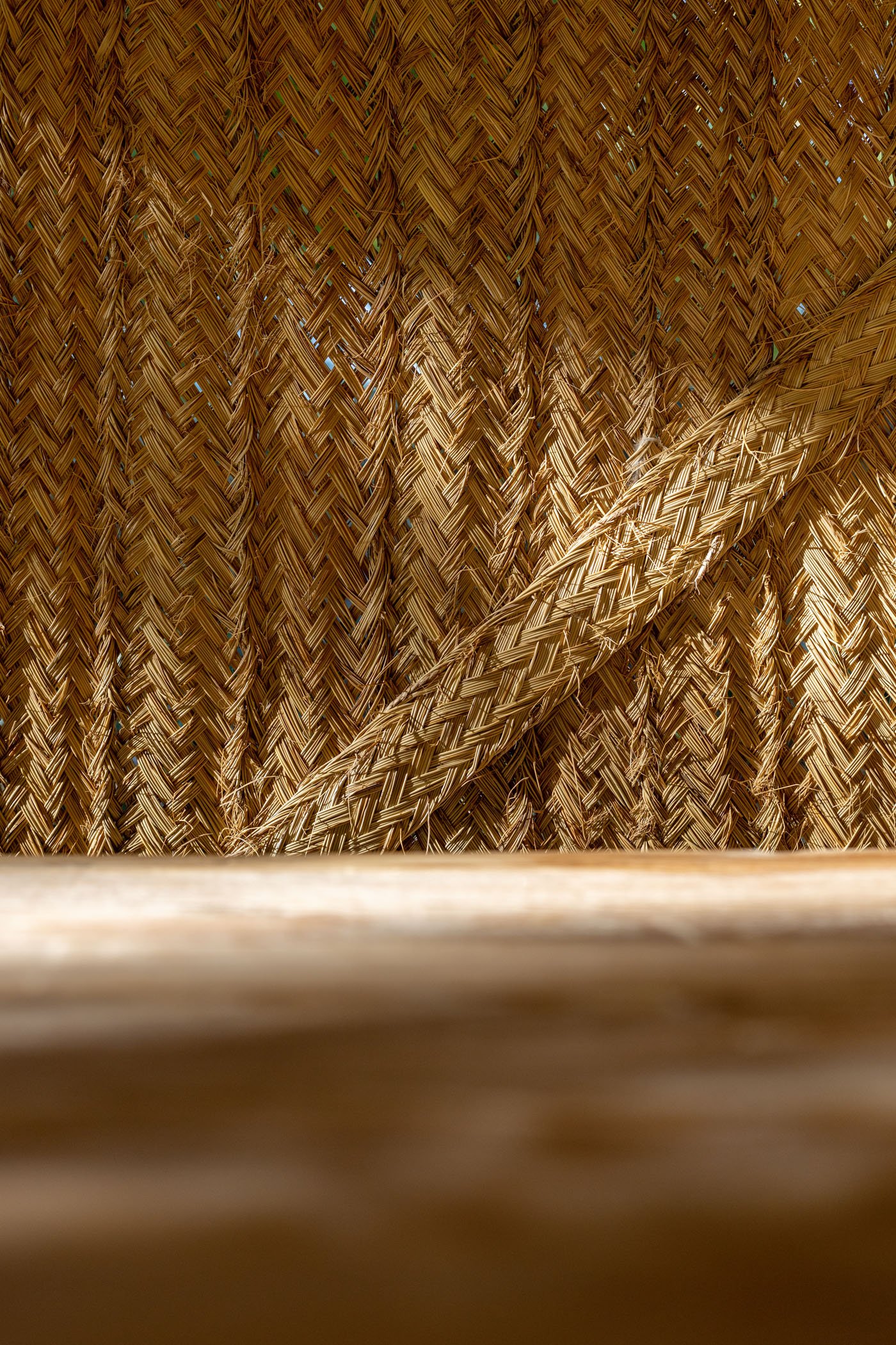 Vista cercana de una pared de cañas de bambú tejidas y una superficie de madera en primer plano.