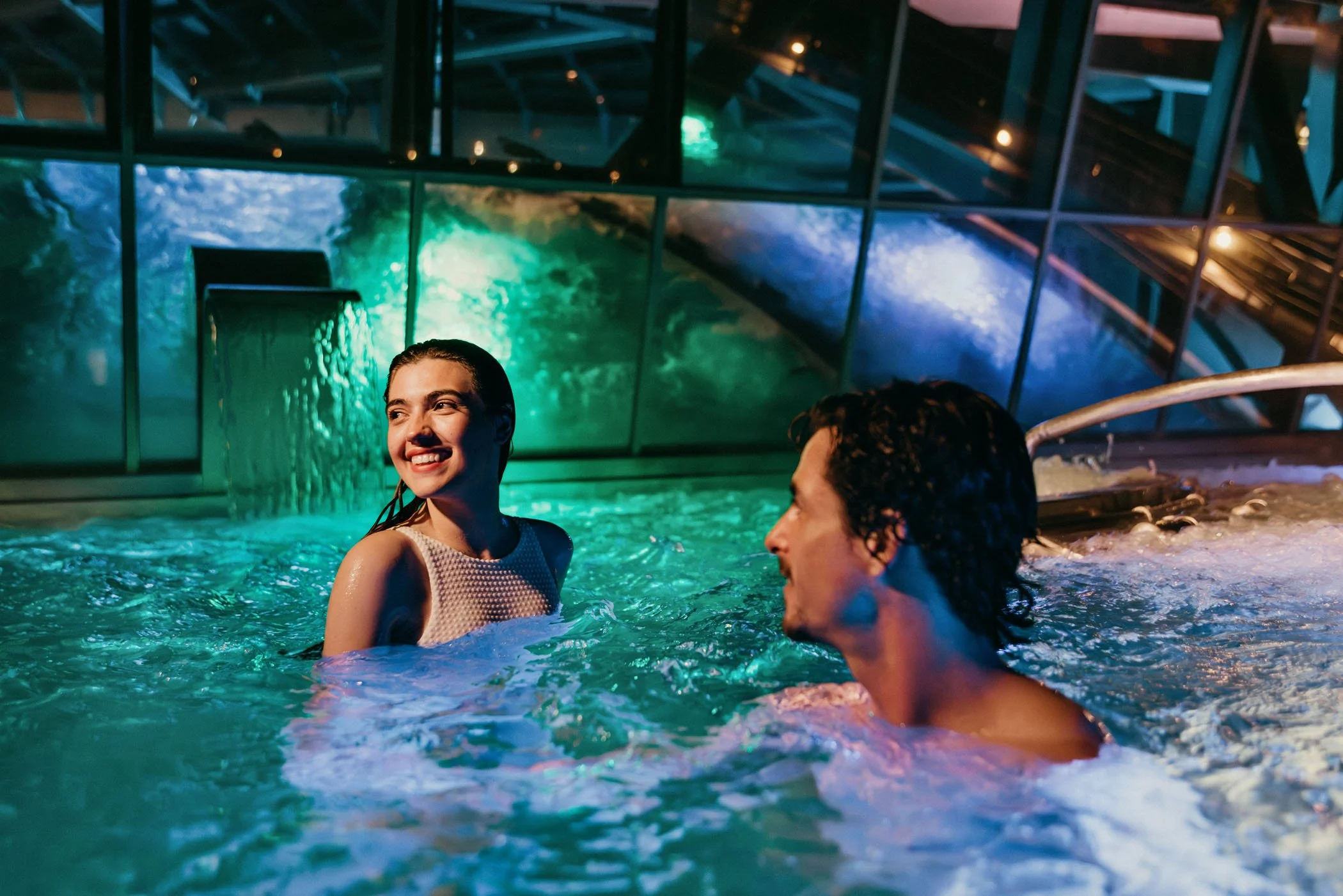 Pareja disfrutando en un jacuzzi en un entorno acuático con iluminación de colores