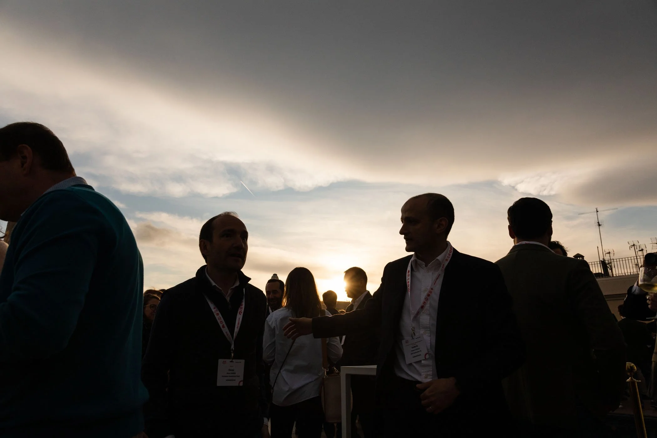 Personas en reunión al atardecer, siluetas con fondo de cielo con nubes y sol
