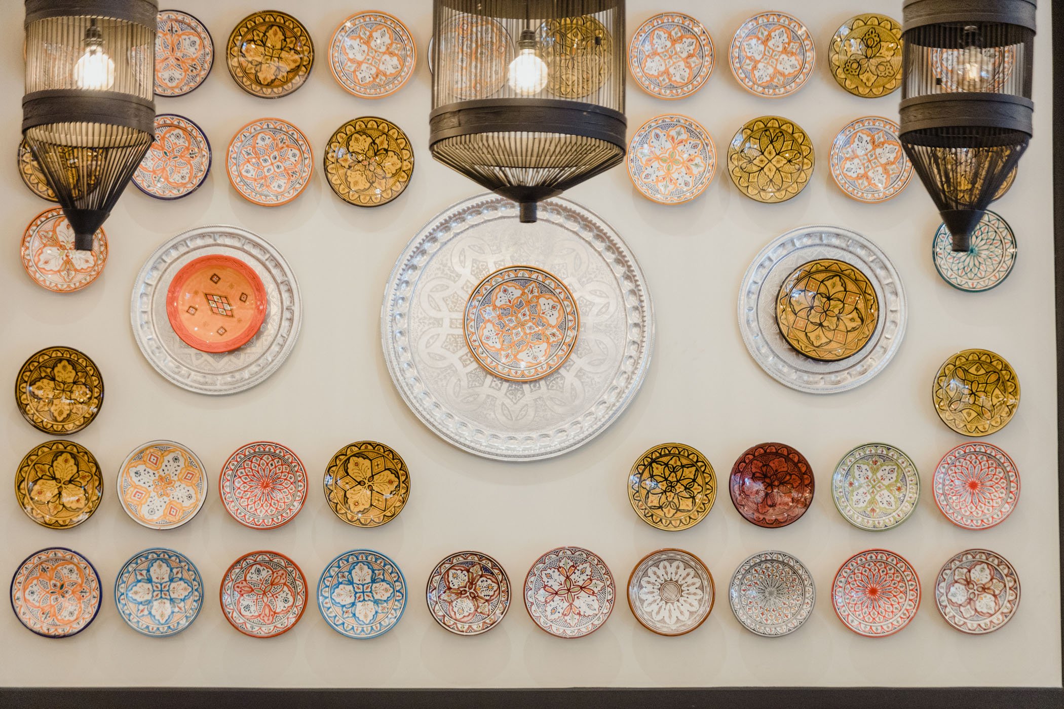 Platos decorativos y lámparas en una pared, con patrones coloridos y detalles detallados.