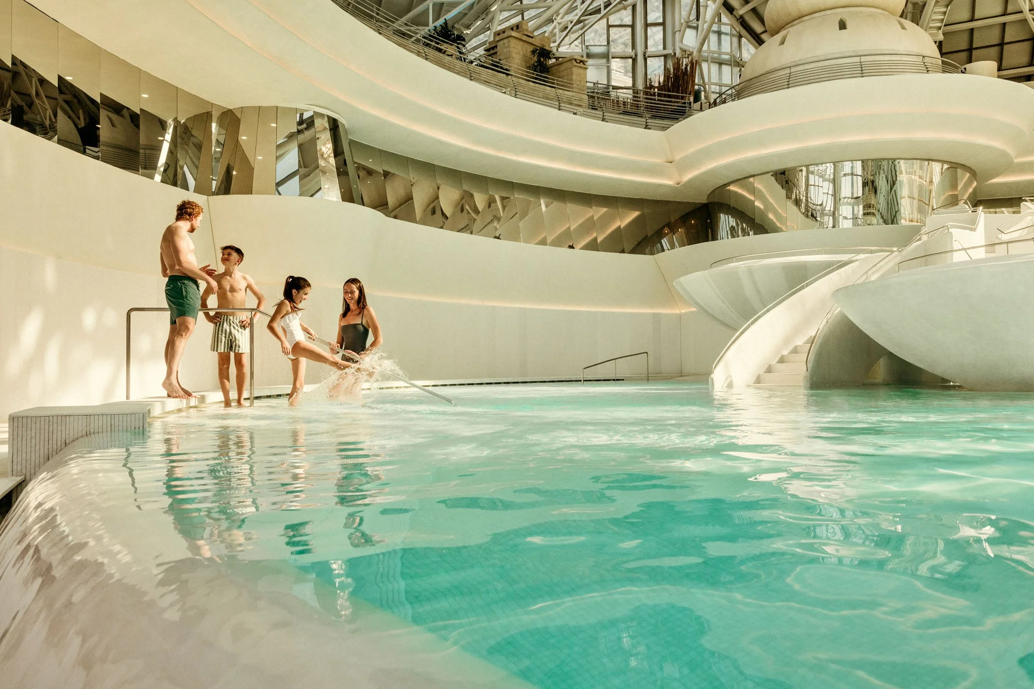 Personas jugando en la piscina interior de un centro recreativo moderno.