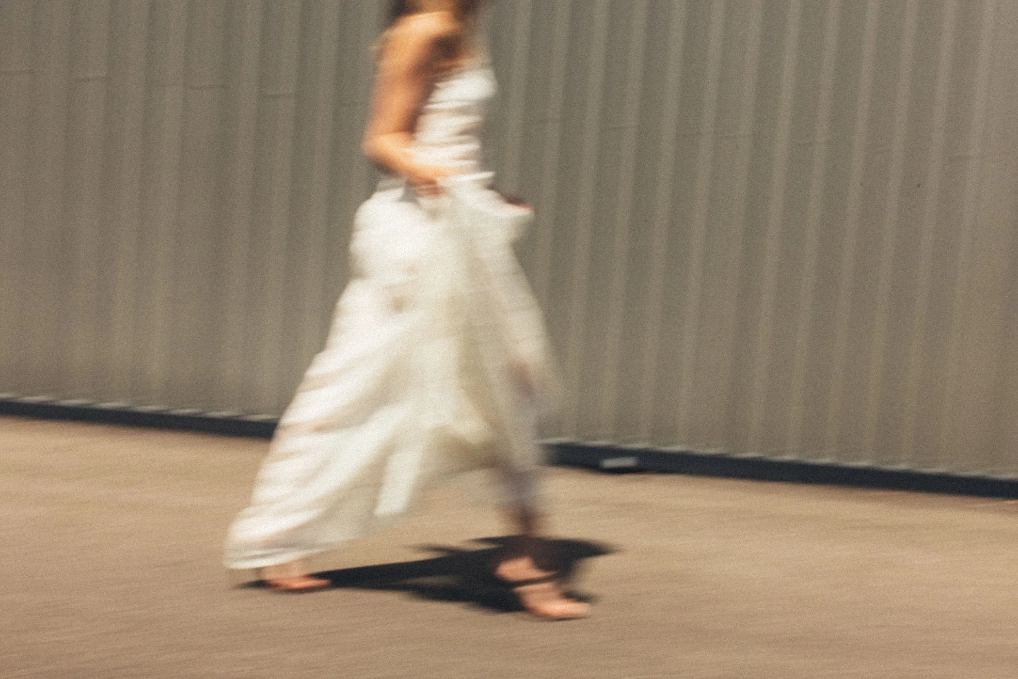 Mujer con vestido largo blanco caminando, imagen borrosa