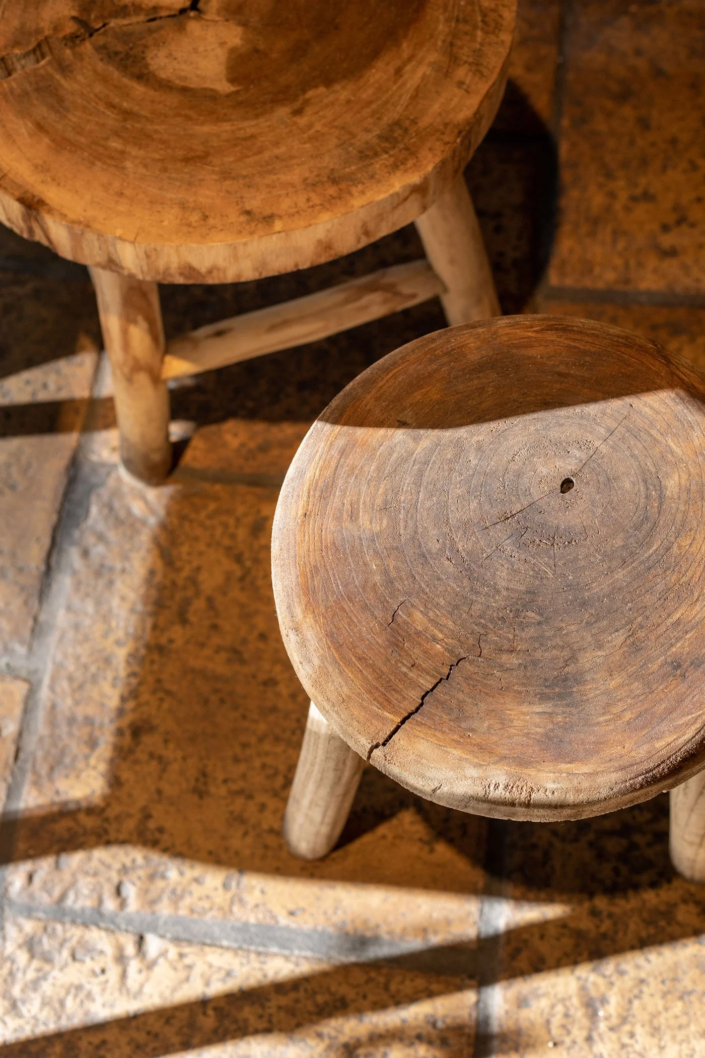 Dos sillas de madera, una vista superior, en una superficie de piedra, con sombras y luz natural.