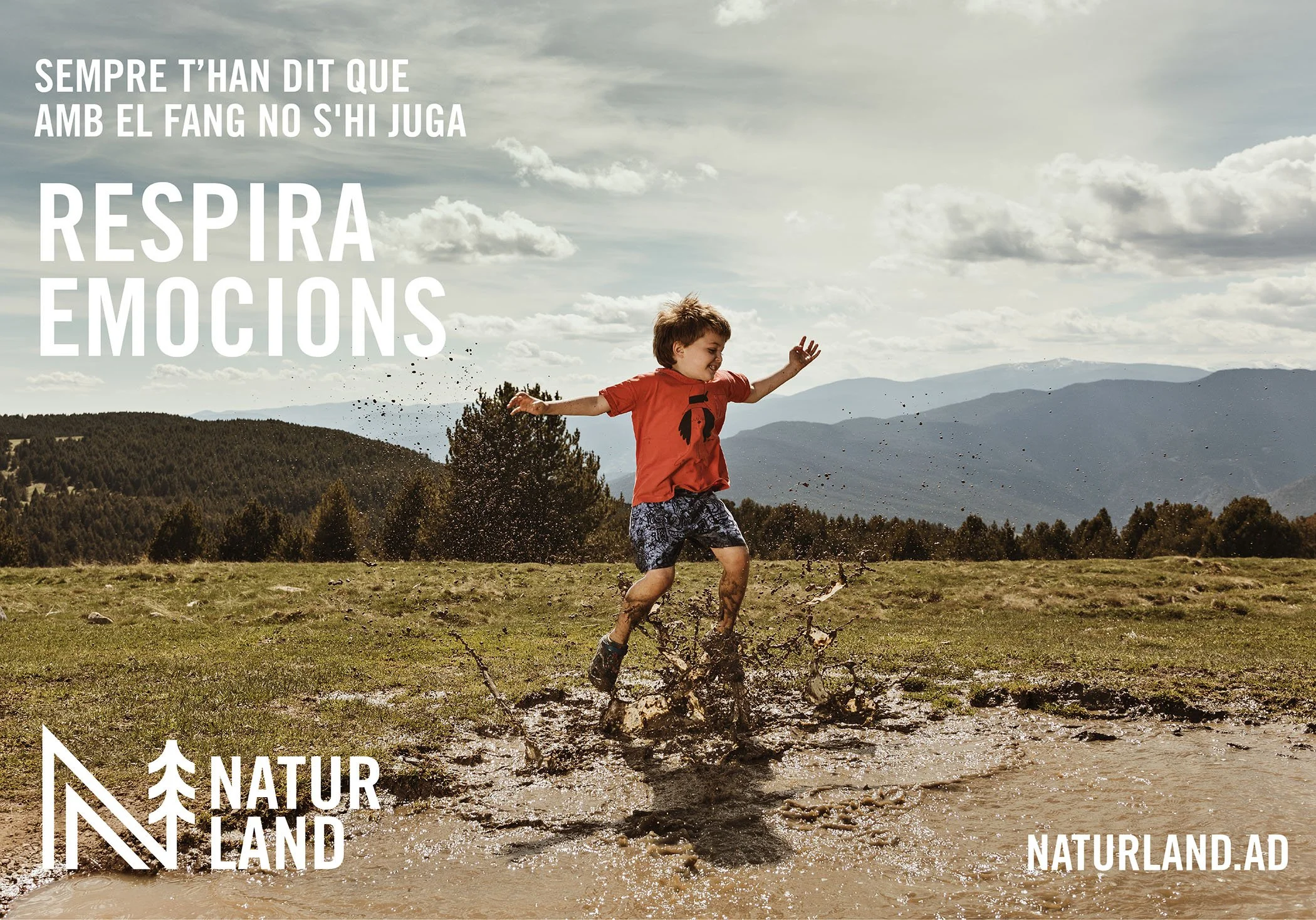 Niño jugando en barro en un campo con montañas y cielo nublado, para la campaña Naturland.