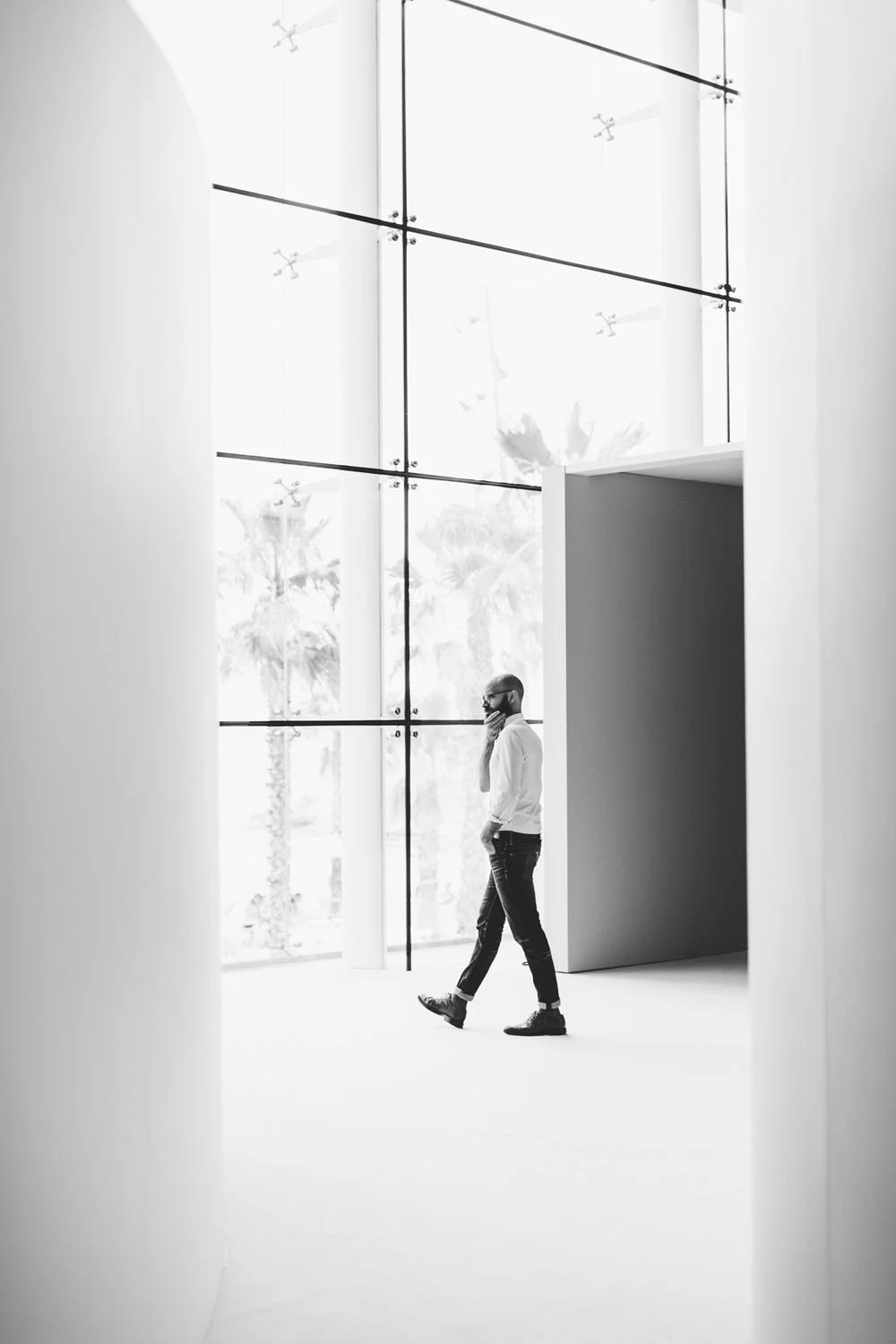 Hombre caminando en un espacio moderno con paredes blancas y ventana grande