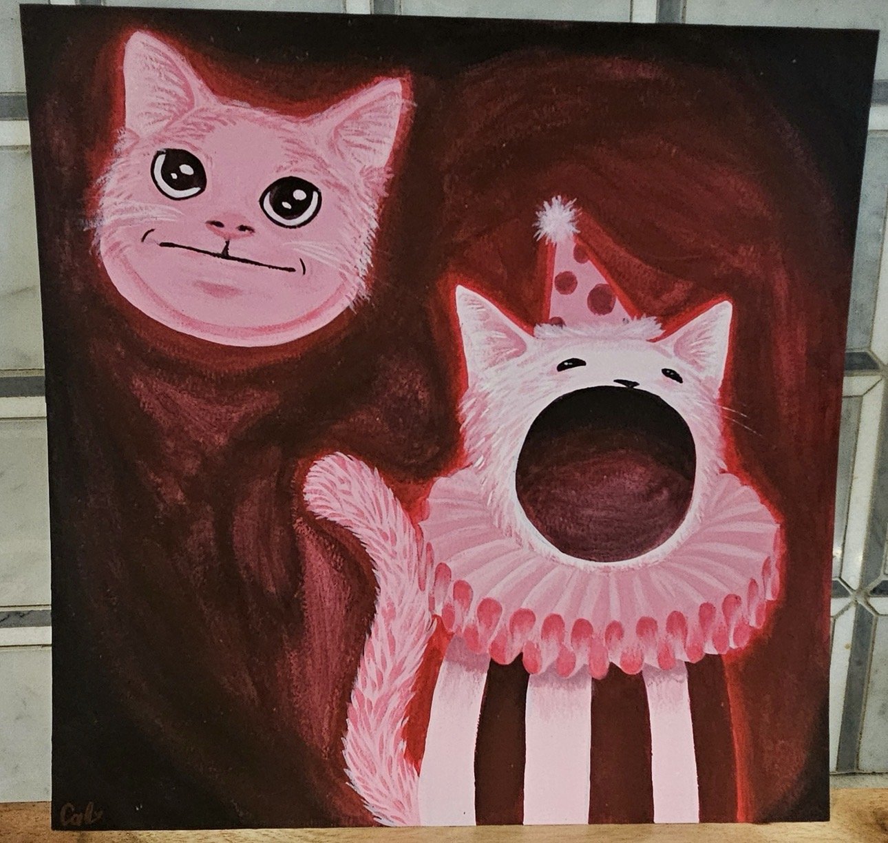 Painted artwork of two cats against a dark red background. One cat has large, expressive eyes and a smiling expression. The other cat is wearing a red party hat with pink polka dots and an orange frilly collar, with its mouth open wide, possibly yawning or meowing.