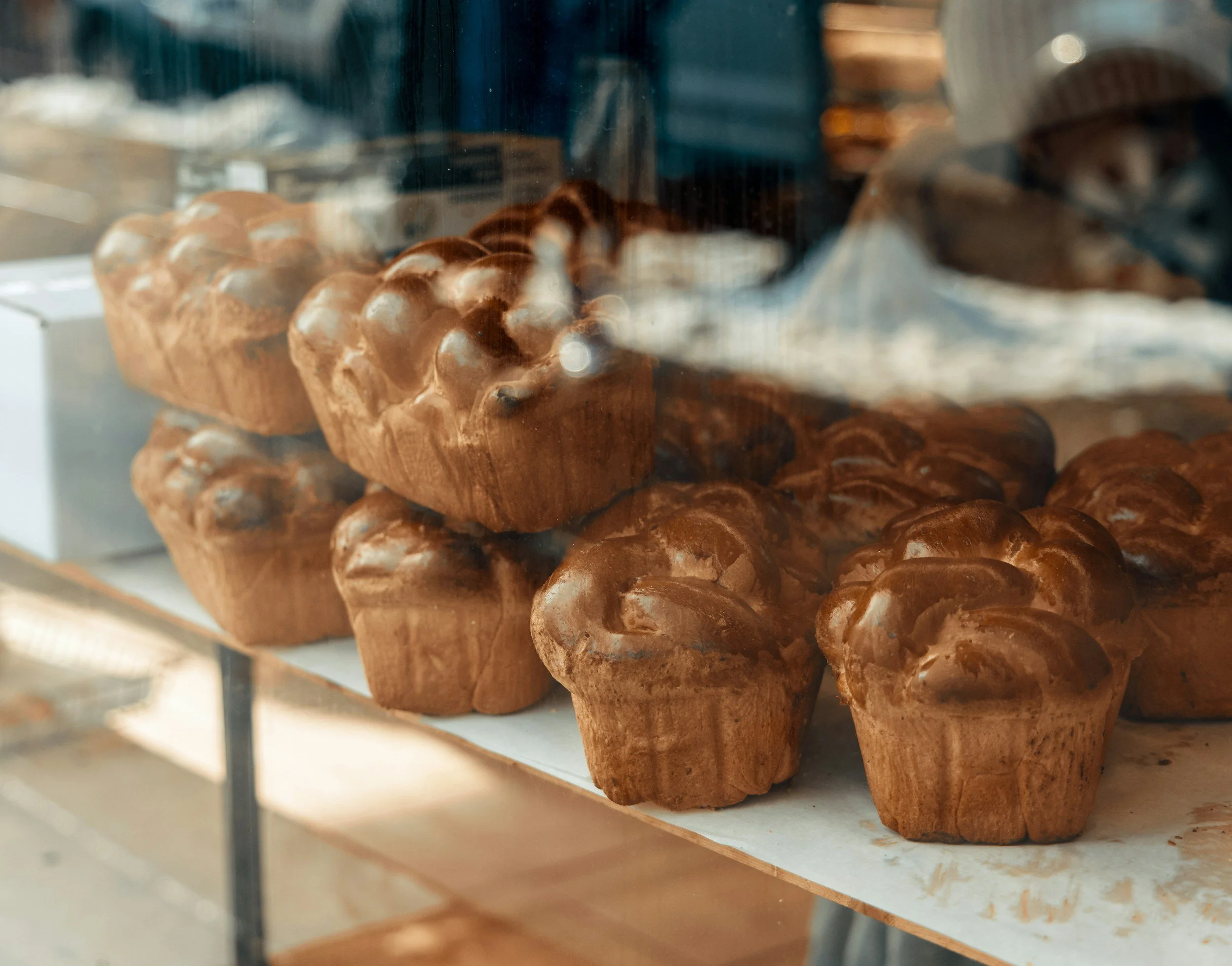 Close-up of a wooden sculpture sculpture of a bear in a store, with other similar wood carvings and items in the background.