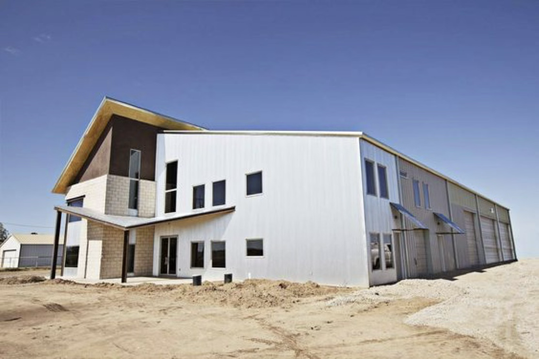 Modern house under construction with exposed foundation and empty surrounding land