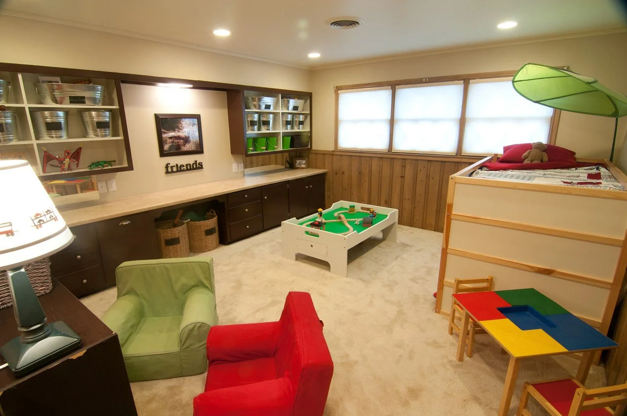 Children's playroom with shelves, storage bins, a foosball table, a bed, and chairs.