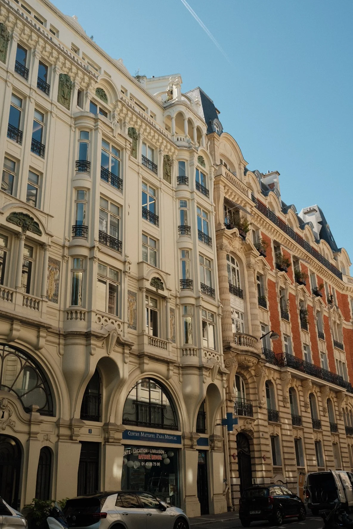 Multi-story European-style building with ornate architecture, balconies, and arched windows, under a clear blue sky.