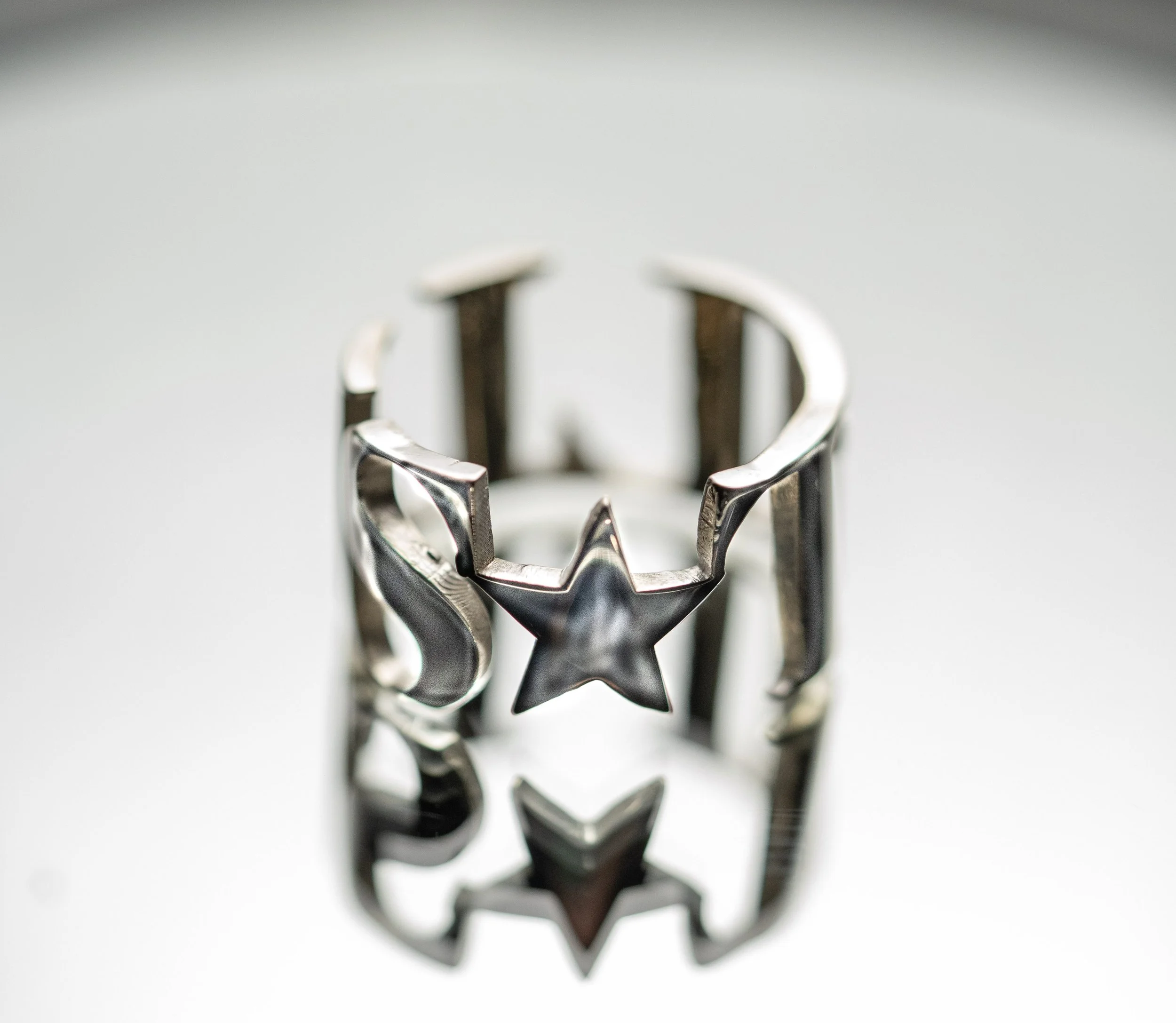 Silver metal ring with a star-shaped cutout in the center, reflecting the surface below.