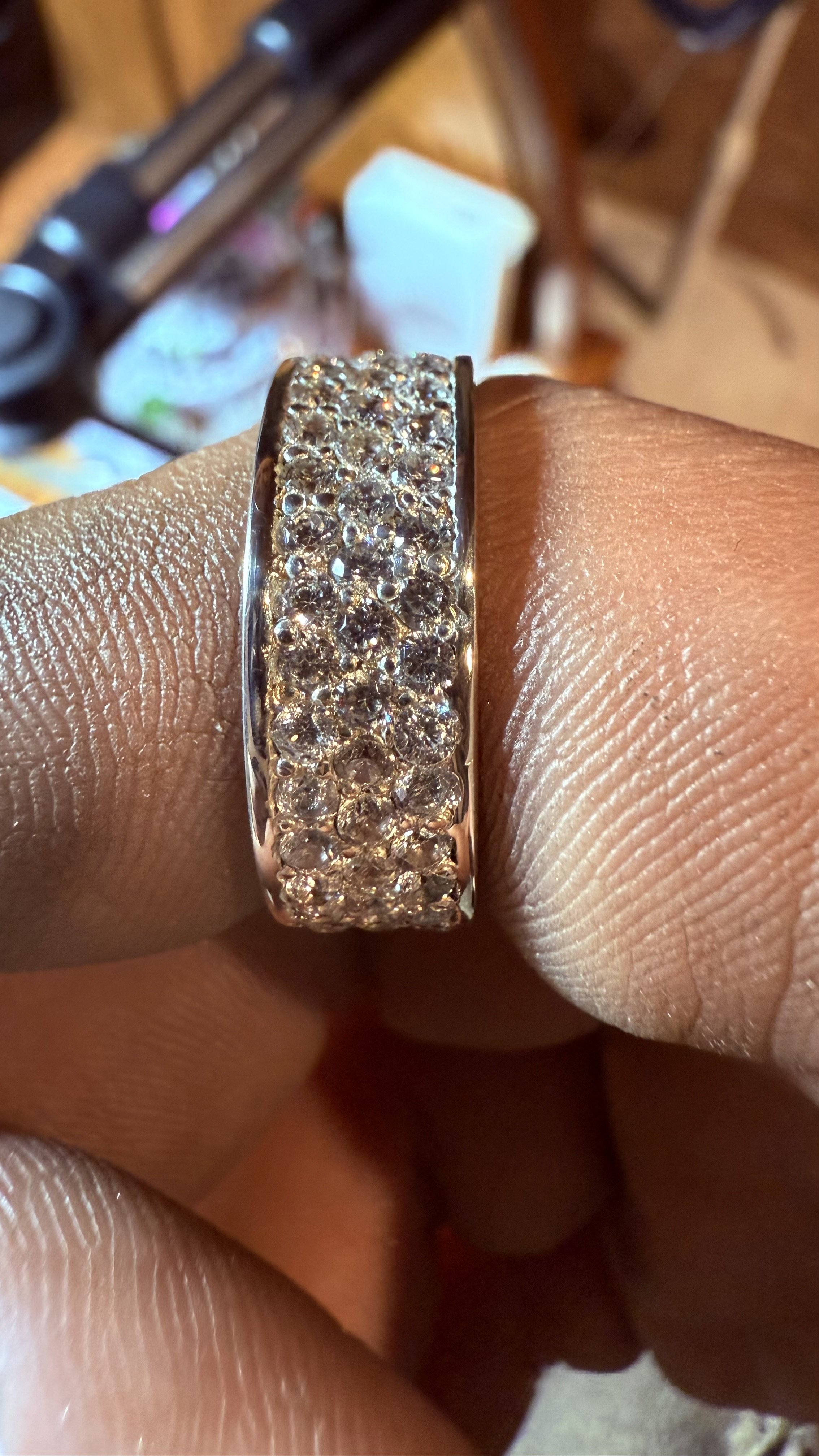 A silver ring encrusted with multiple small diamonds worn on a finger.