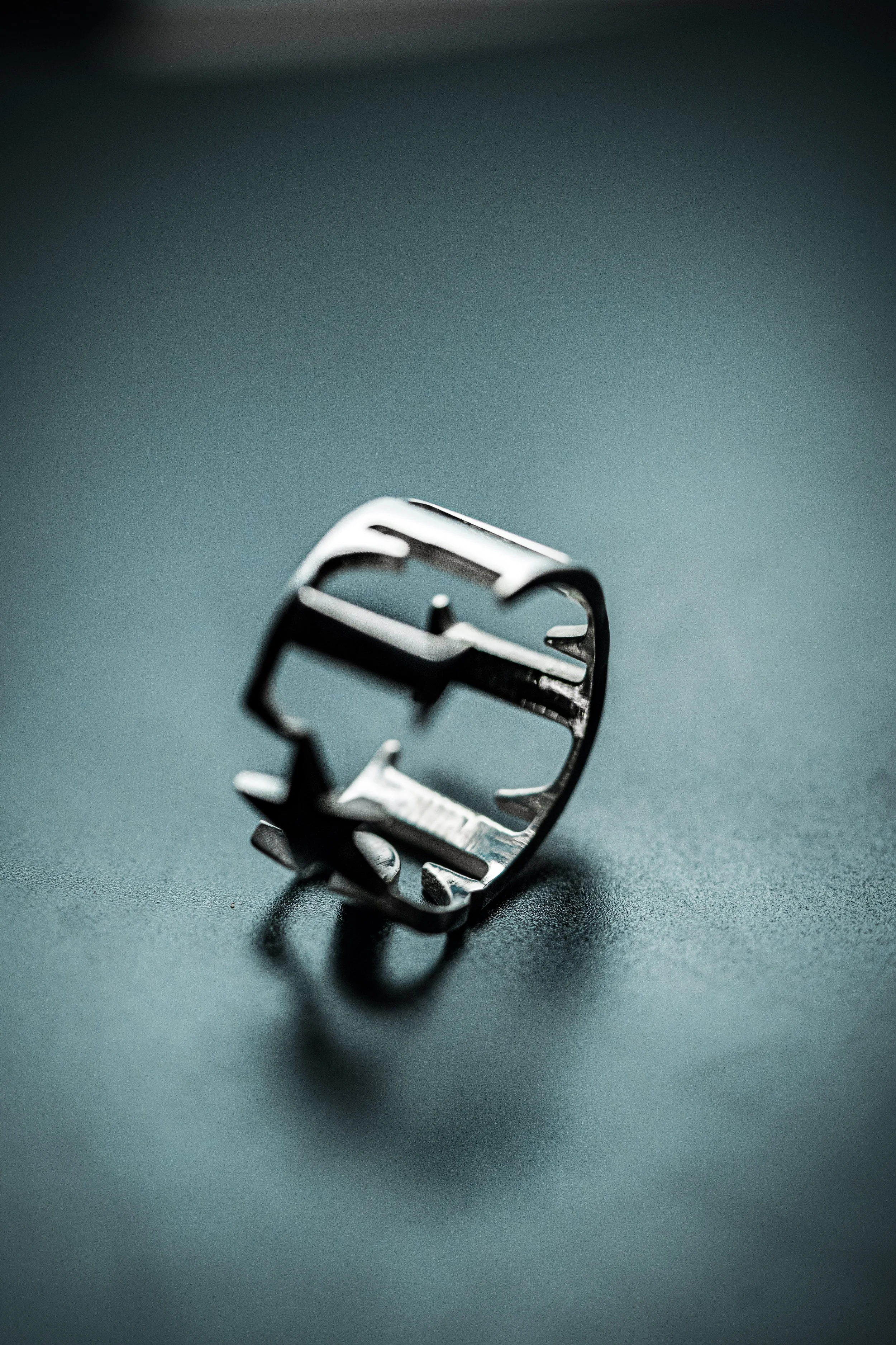 A close-up of a metallic safety razor component on a dark surface