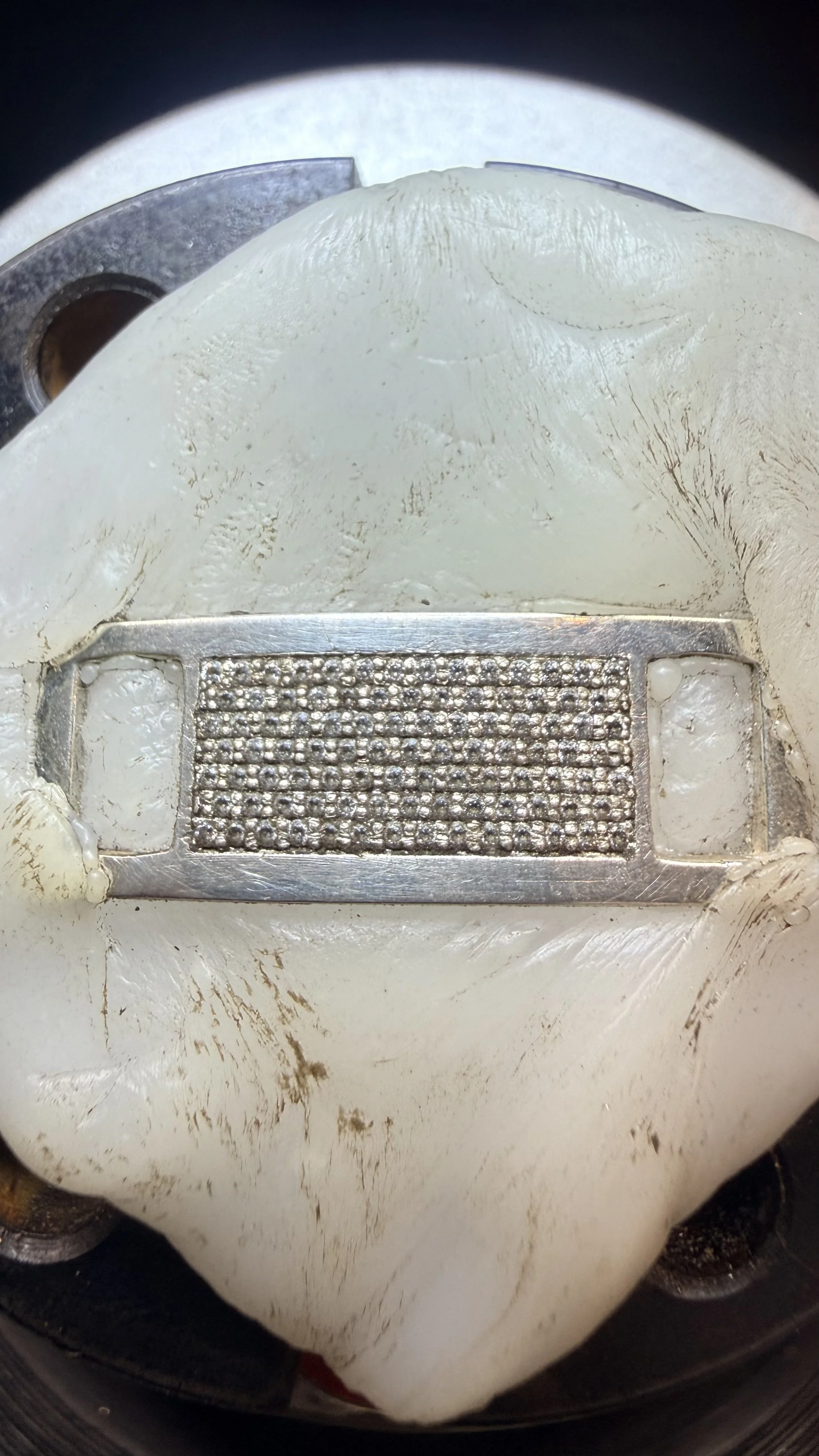 Close-up of a roulette wheel's center, showing the metal number segment with small diamonds, surrounded by a white surface with scratches and dirt.