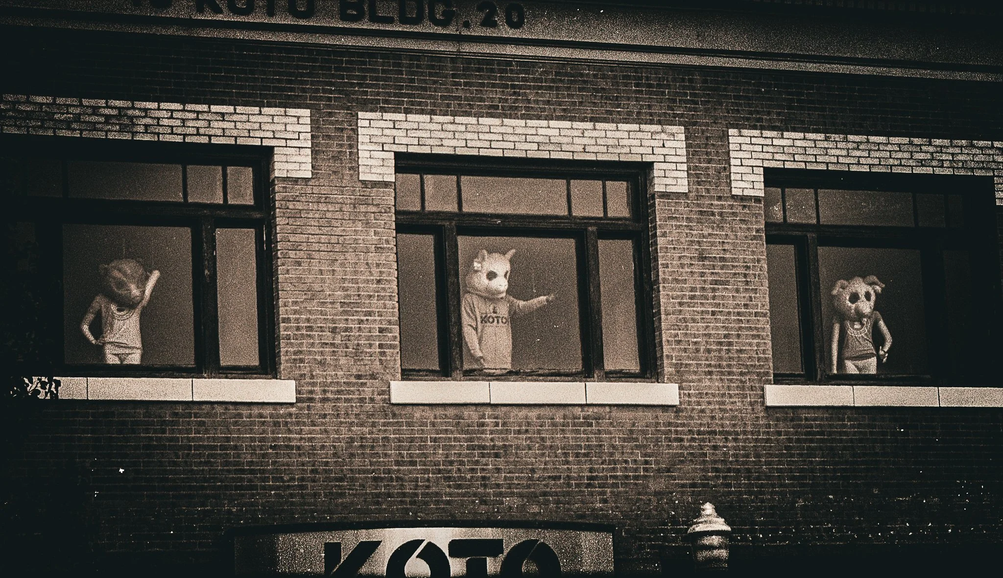 Three people wearing animal mascot costumes looking out of windows.