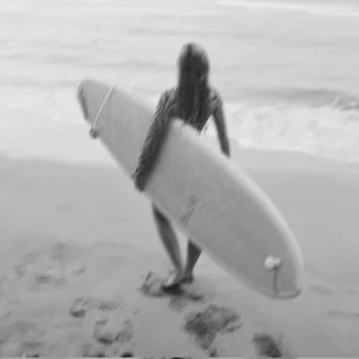 Women carrying a surfboard at Jobos Beach in Isabela, PR. Alexandra Swansen, owner of Twin Fin Coffee, in Aguadilla, PR