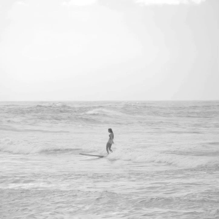 A woman surfing on a small wave in the ocean at Middles Beach in Isabela, PR.