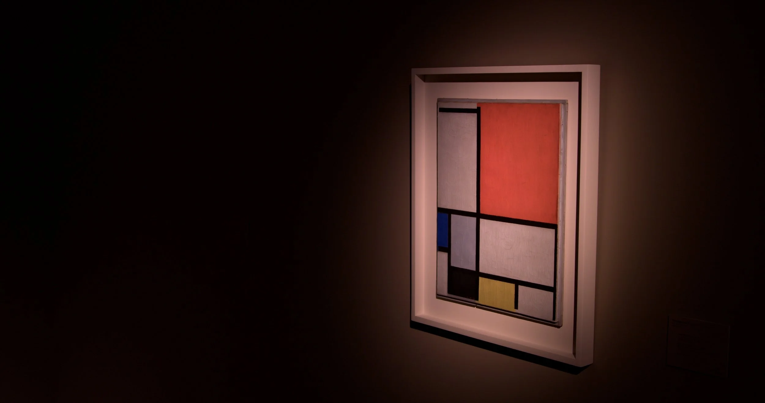 Framed artwork inspired by Piet Mondrian, featuring a grid with colorful rectangular blocks in red, blue, yellow, and black.