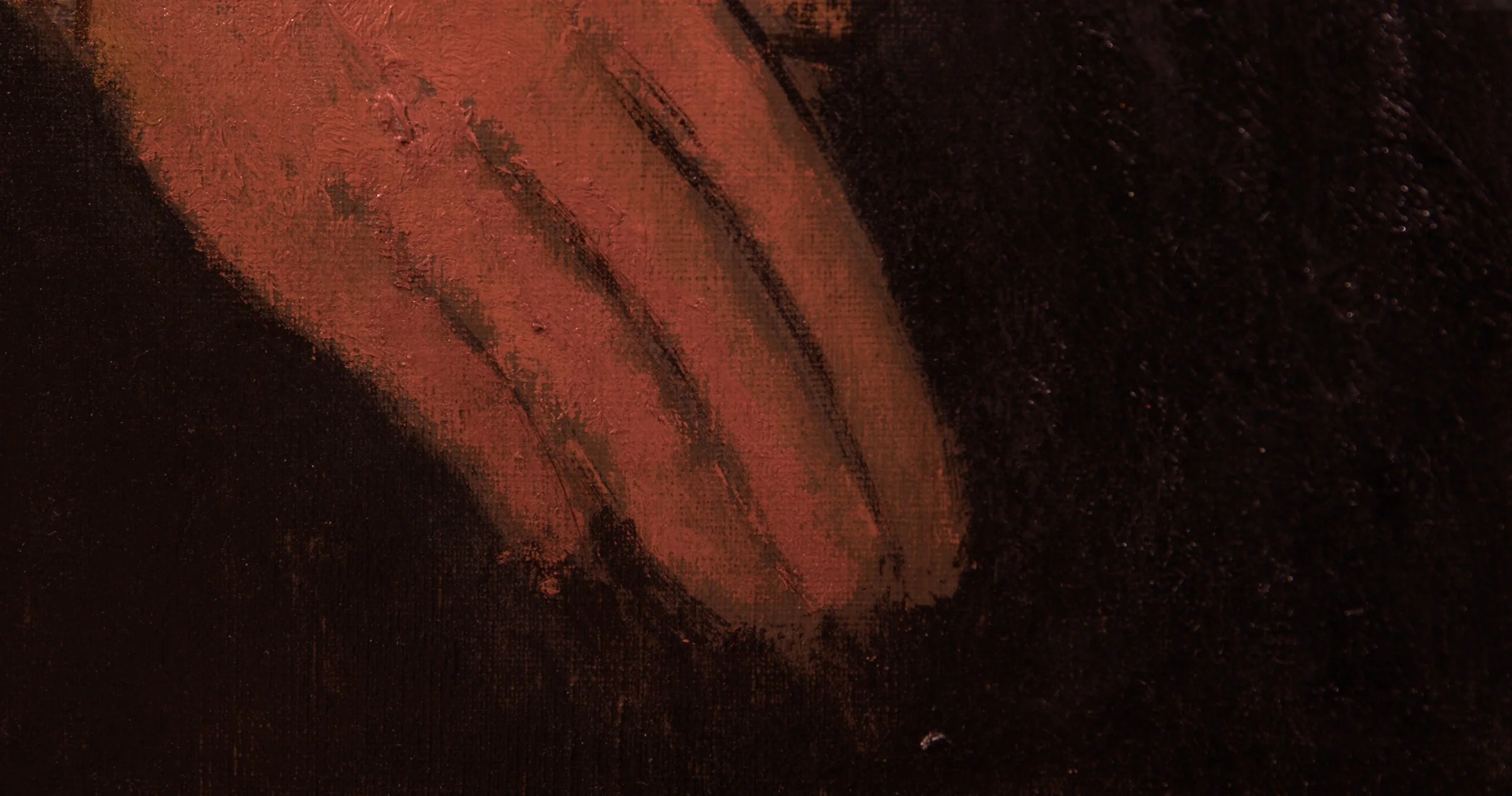 Close-up of a hand with dark reddish-brown paint on the fingers and palm, on a dark surface.