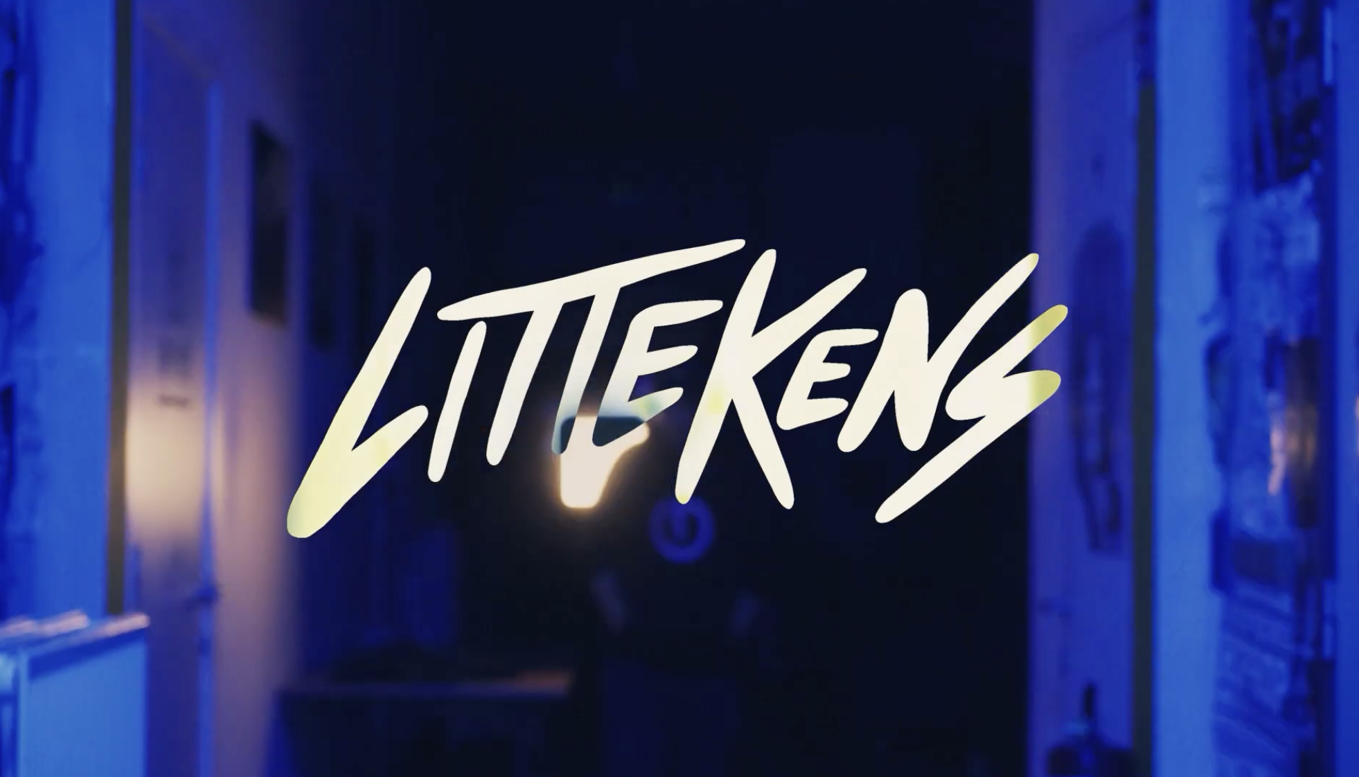 Neon sign with the word 'LITTEKENS' in stylized script, glowing in yellowish-white against a dark and blue-lit background.