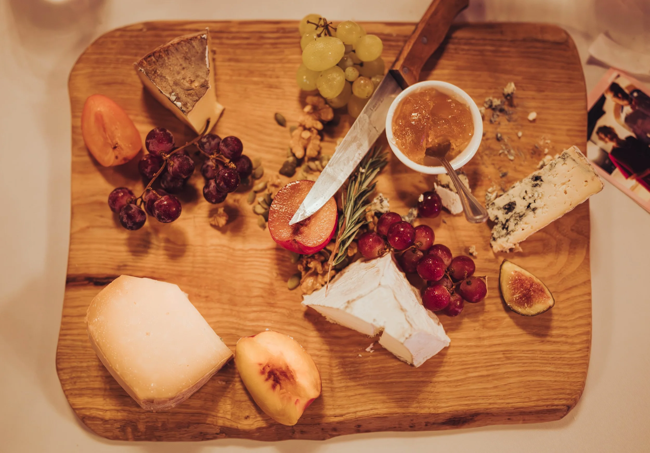 Plateau de fromages, raisins, figues, miel, et fruits sur une planche en bois lors d'un mariage à l'Orangerie des Demoiselles de Frouzins près de Toulouse, en Occitanie. 