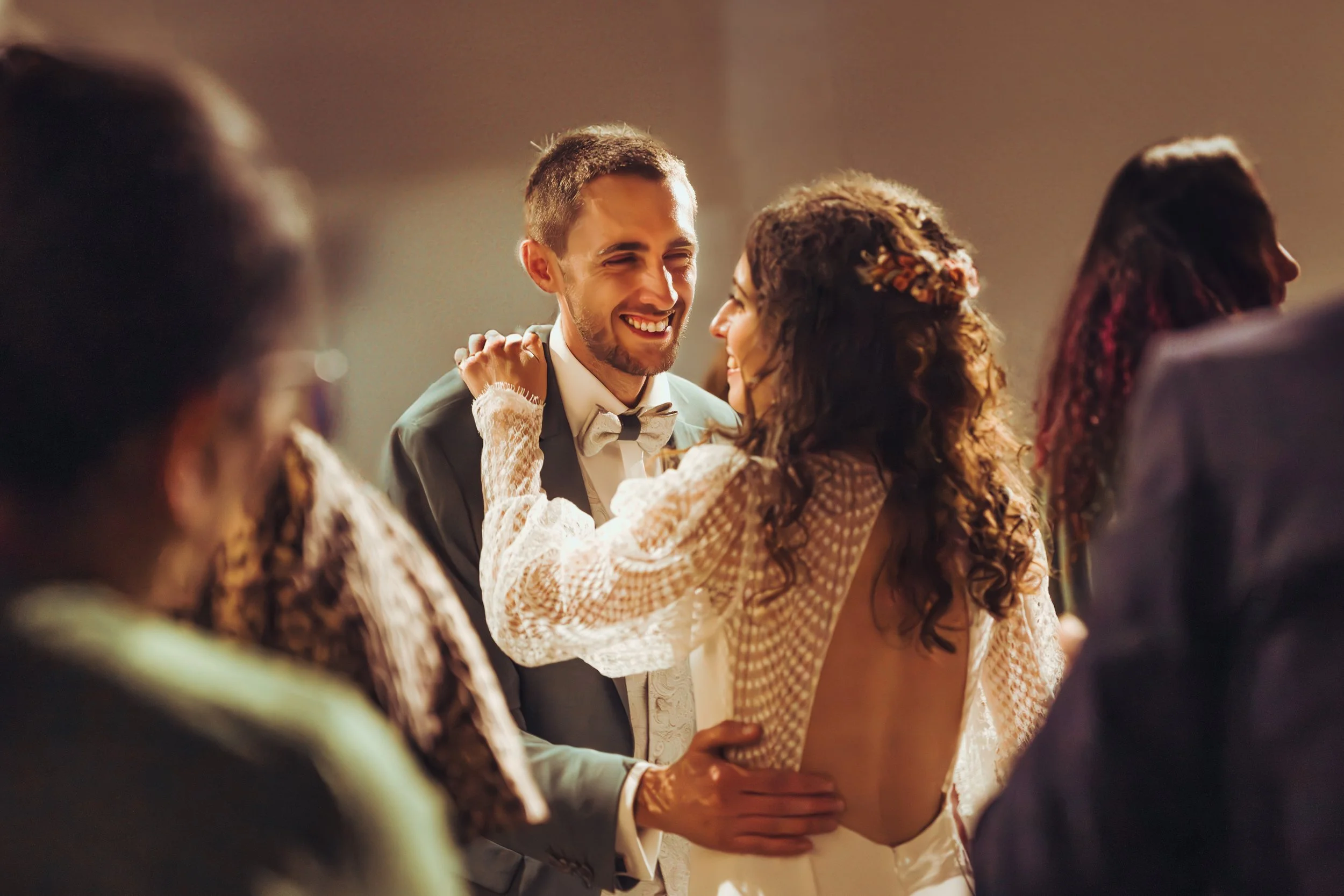 Un couple dansant et souriant lors de leur mariage, entouré d'autres personnes dans une salle bien éclairée, au domaine de Gailhaguet proche de Toulouse, en Occitanie. 