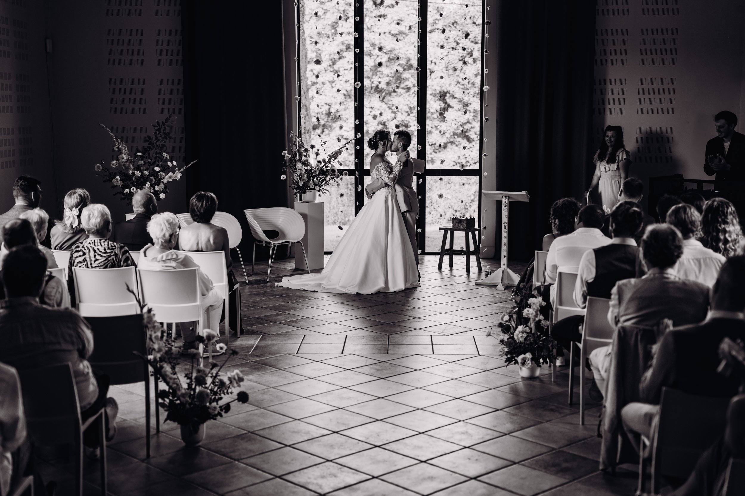 Baiser des mariés lors de leur cérémonie laique au Mas des Canelles proche de Toulouse, en Occitanie. Photographie en noir et blanc.