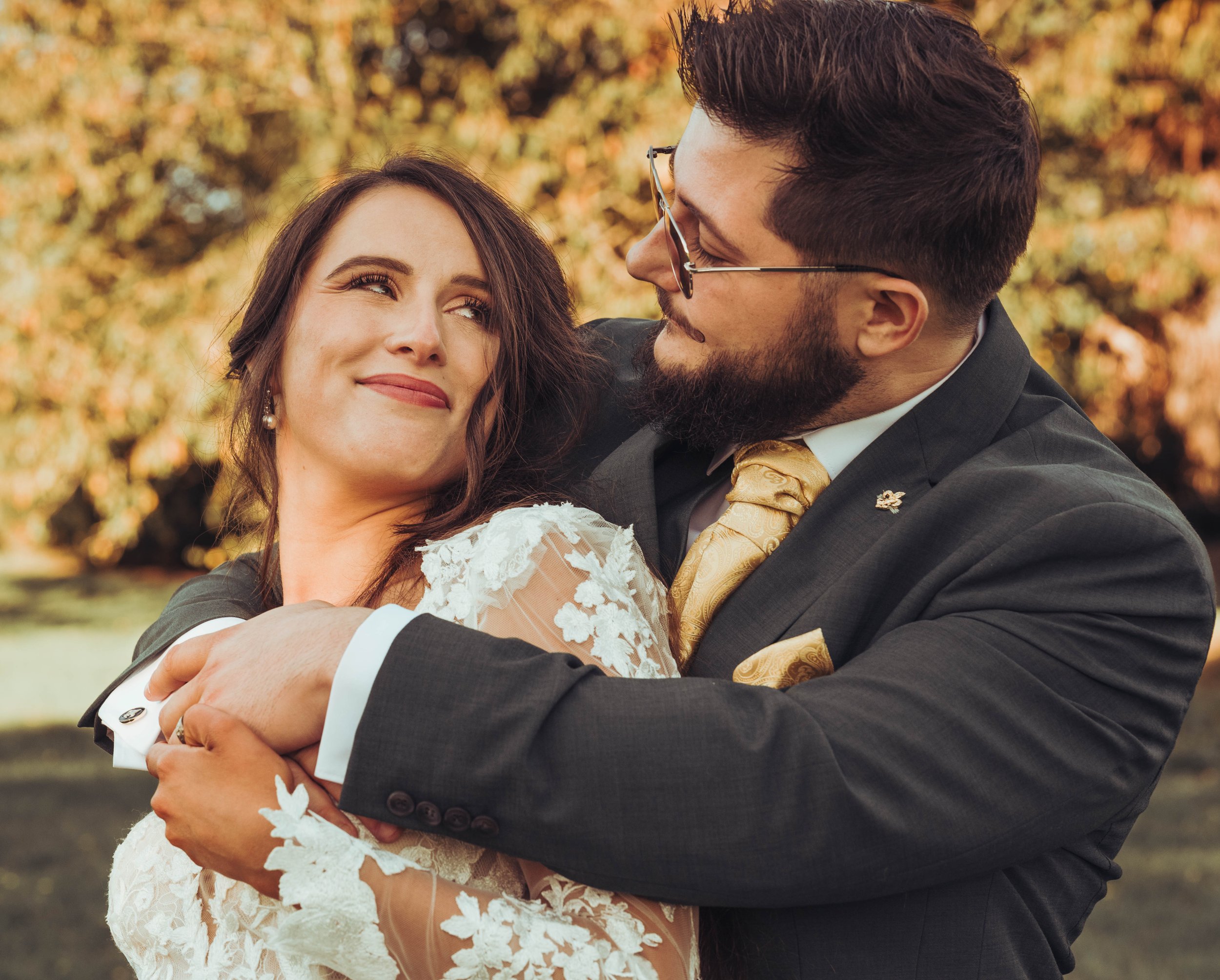 Un couple en habits de mariage lors de leur séance de couple au château de Fajac la relenque qui s'étreignent dans un parc aux couleurs automnales.