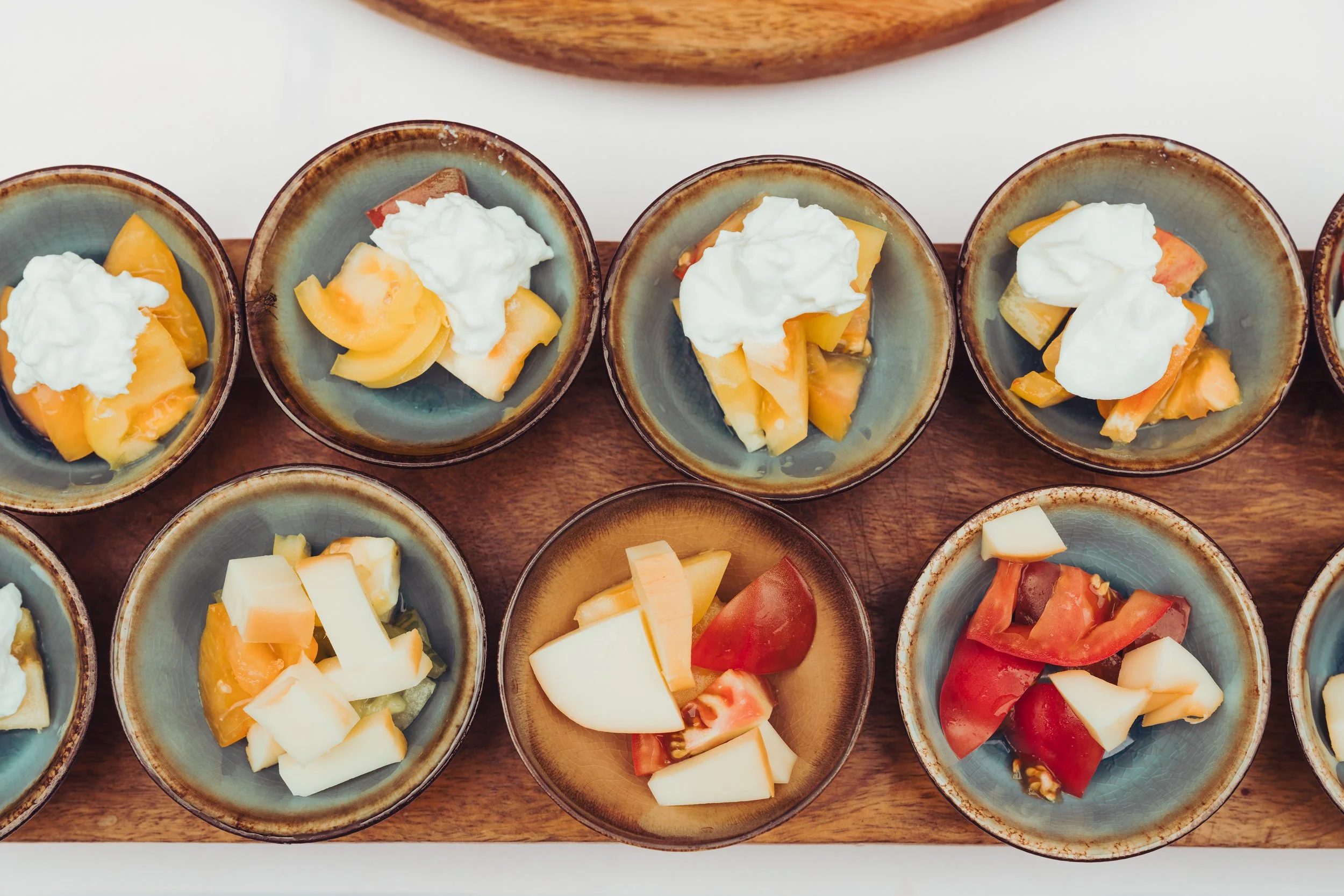 Plateau avec différentes portions de fromage et de tomates dans de petites assiettes en céramique servi lors d'un mariage au Mas des Canelles 