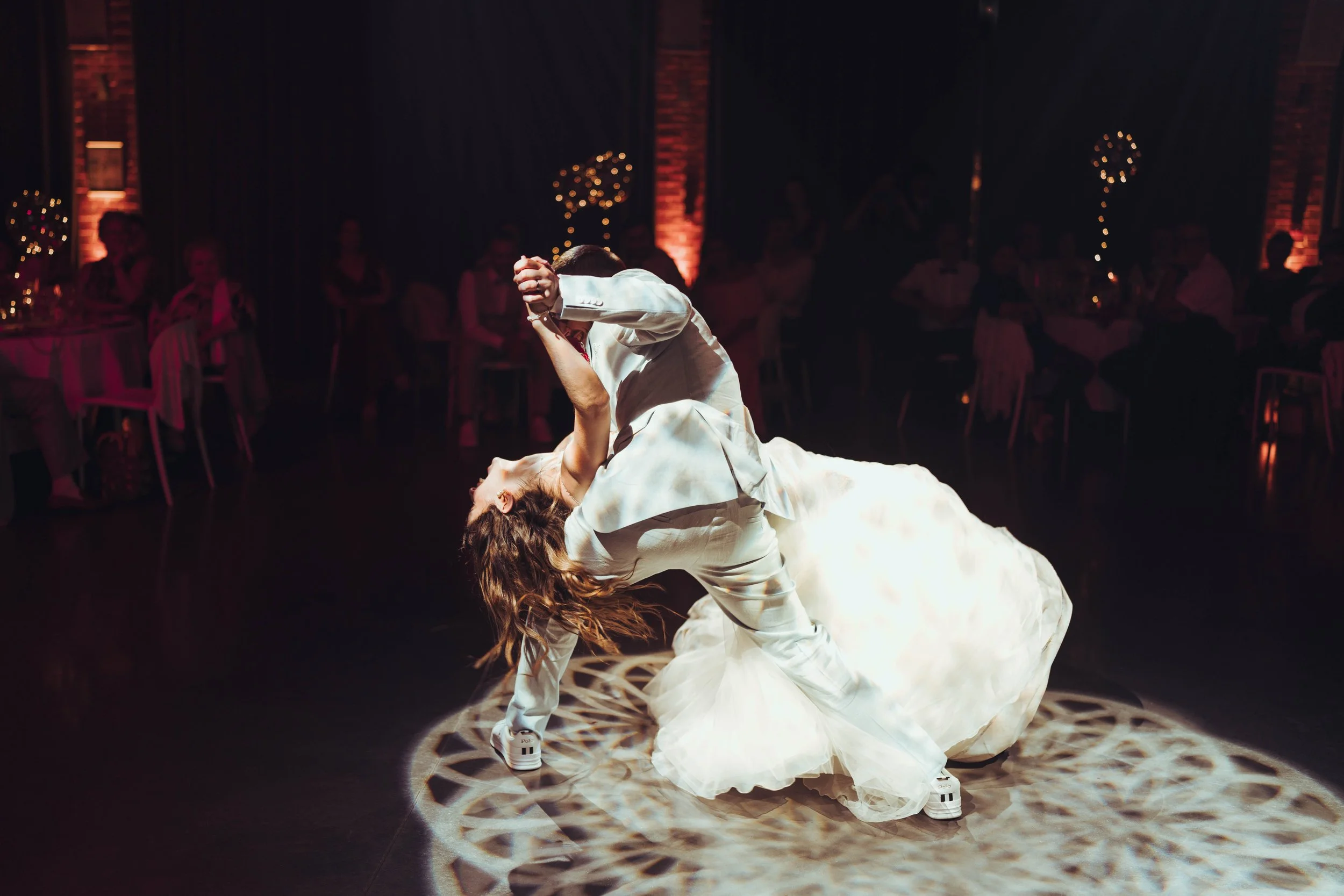 Un couple en tenue de mariage danse lors d'une réception au Mas Tolosa, proche de Toulouse, dans la magnifique salle décorée avec des lumières d'ambiance, et des invités en folie pour leur ouverture de balle 