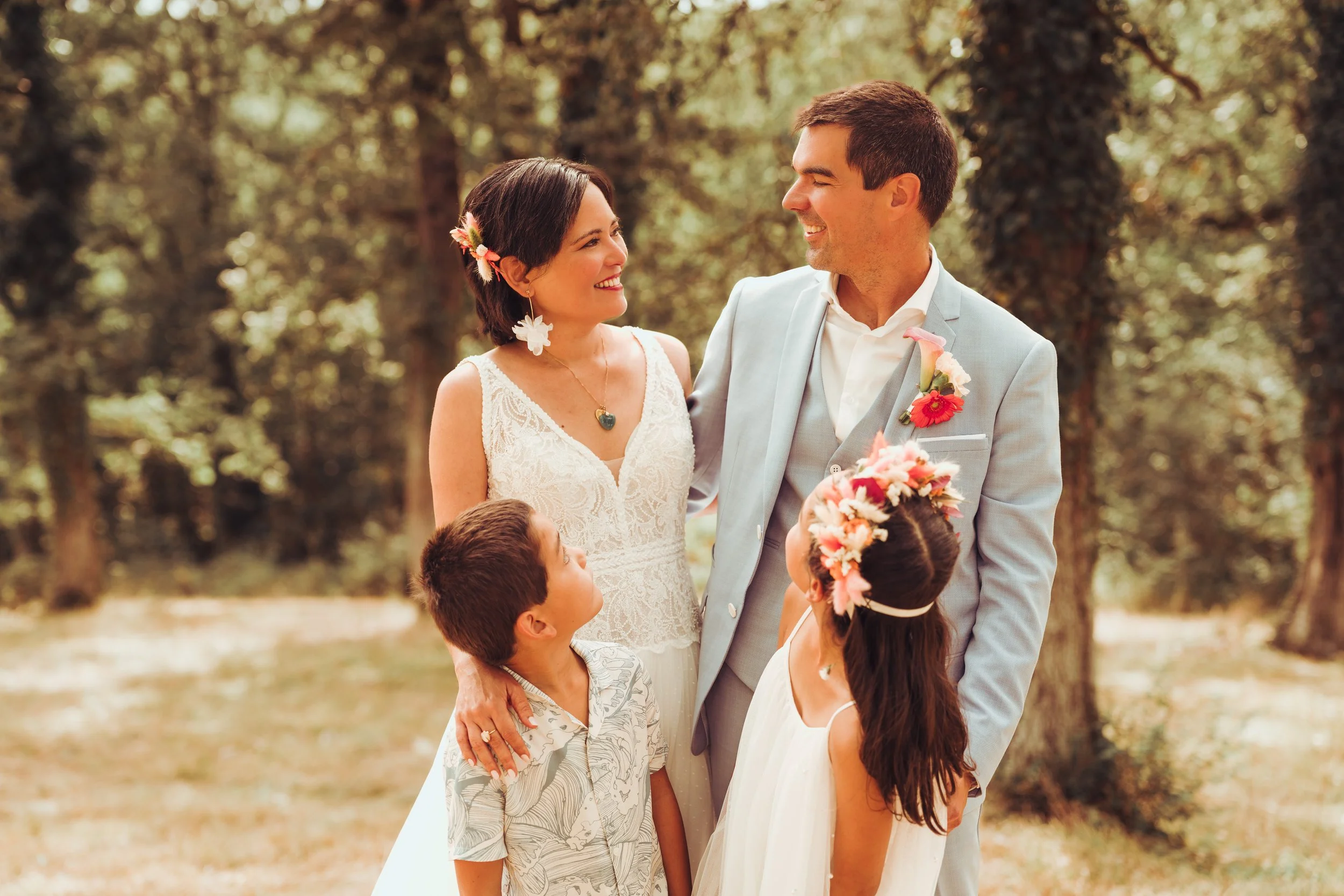 Un couple marié avec deux enfants dans la forêt de la métairie du Fusté près de Toulouse, en Occitanie, lors d'un mariage, avec des fleurs et des vêtements de cérémonie.