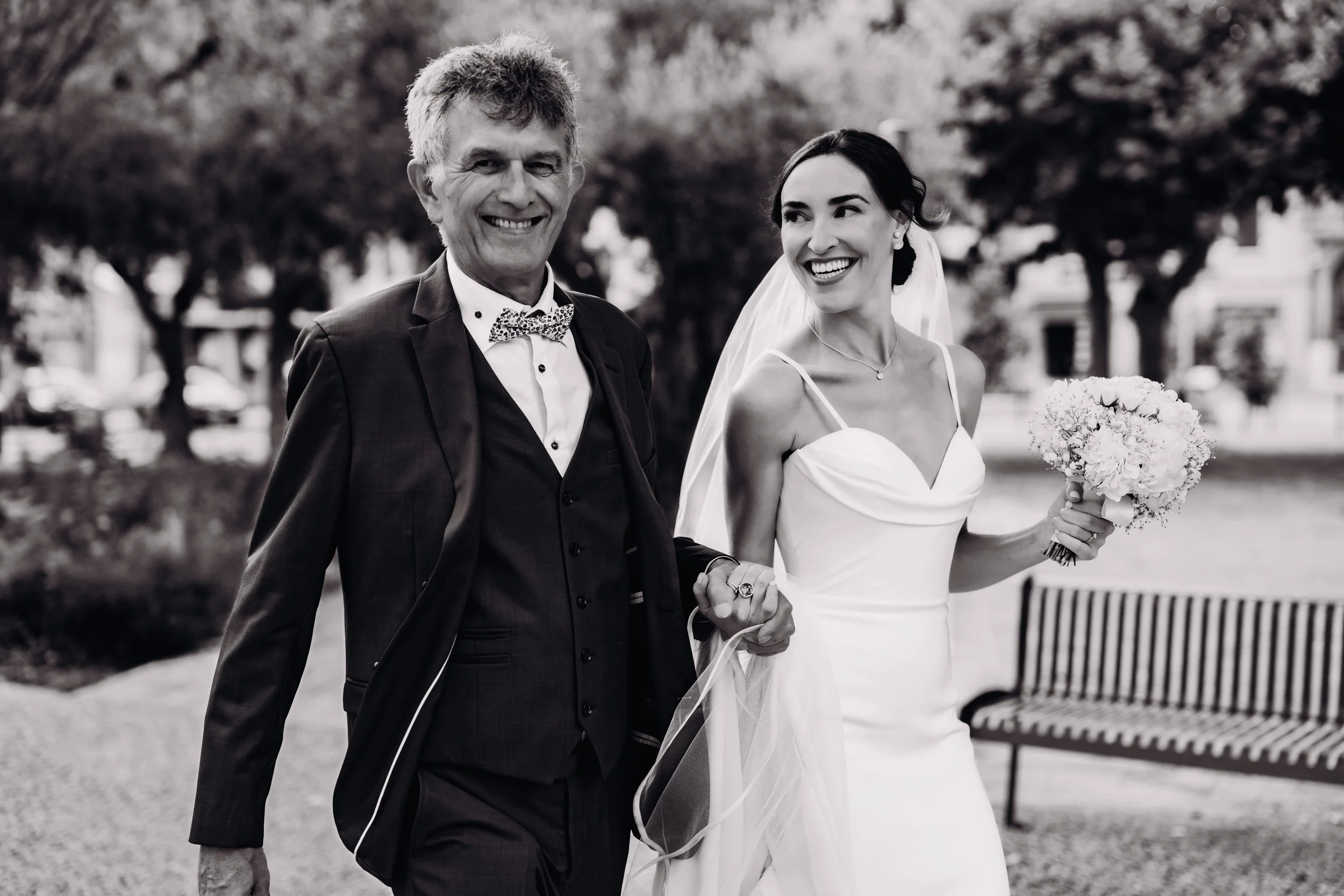 La mariée se rend à l'église de Seysse au bras de son père pour son mariage religieux avant de continuer la fête à l'Orangerie des Demoiselles près de Toulouse, en Occitanie. 