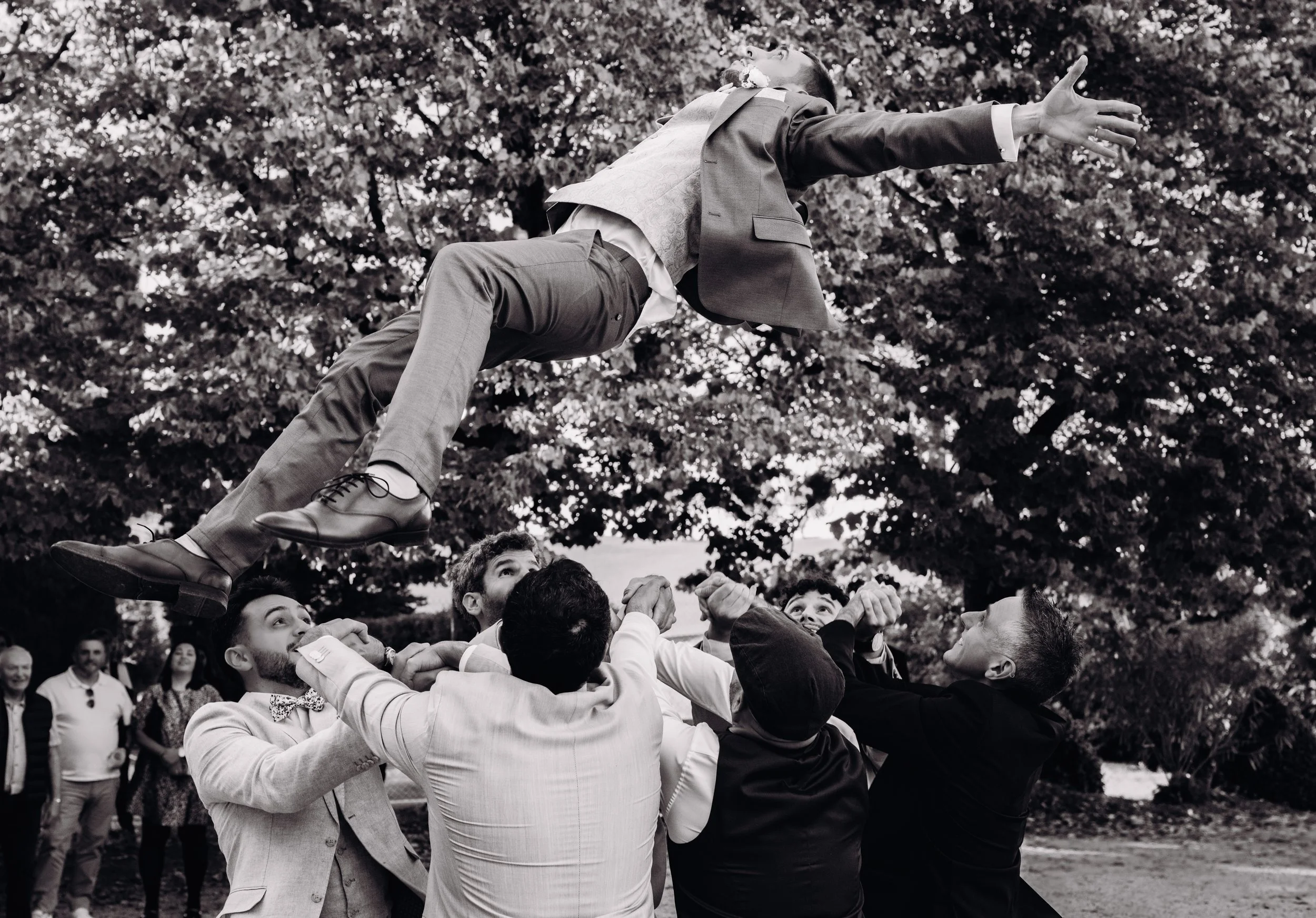 Un groupe de personnes en costume participe à une fête ou une célébration en levant le marié dans les airs au domaine de Gailhaguet