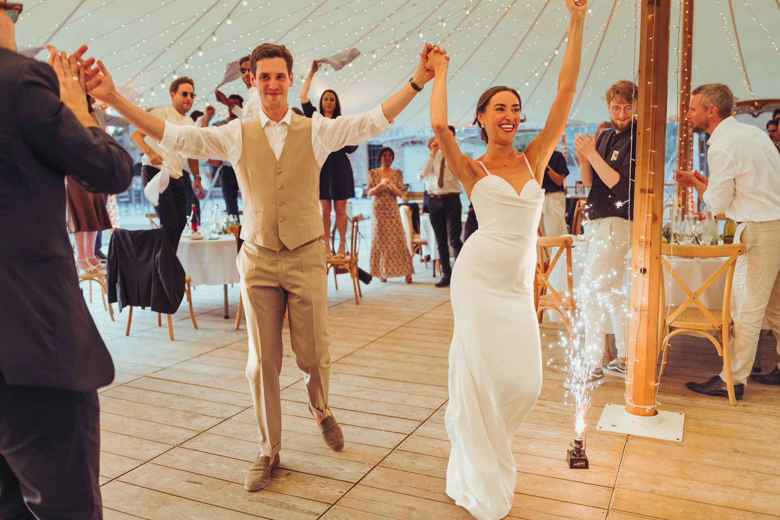 Les mariés entrent sous le chapiteau de l'Orangerie des Demoiselles de Frouzins, près de Toulouse, en Occitanie, pour lancer leur soirée festive. 