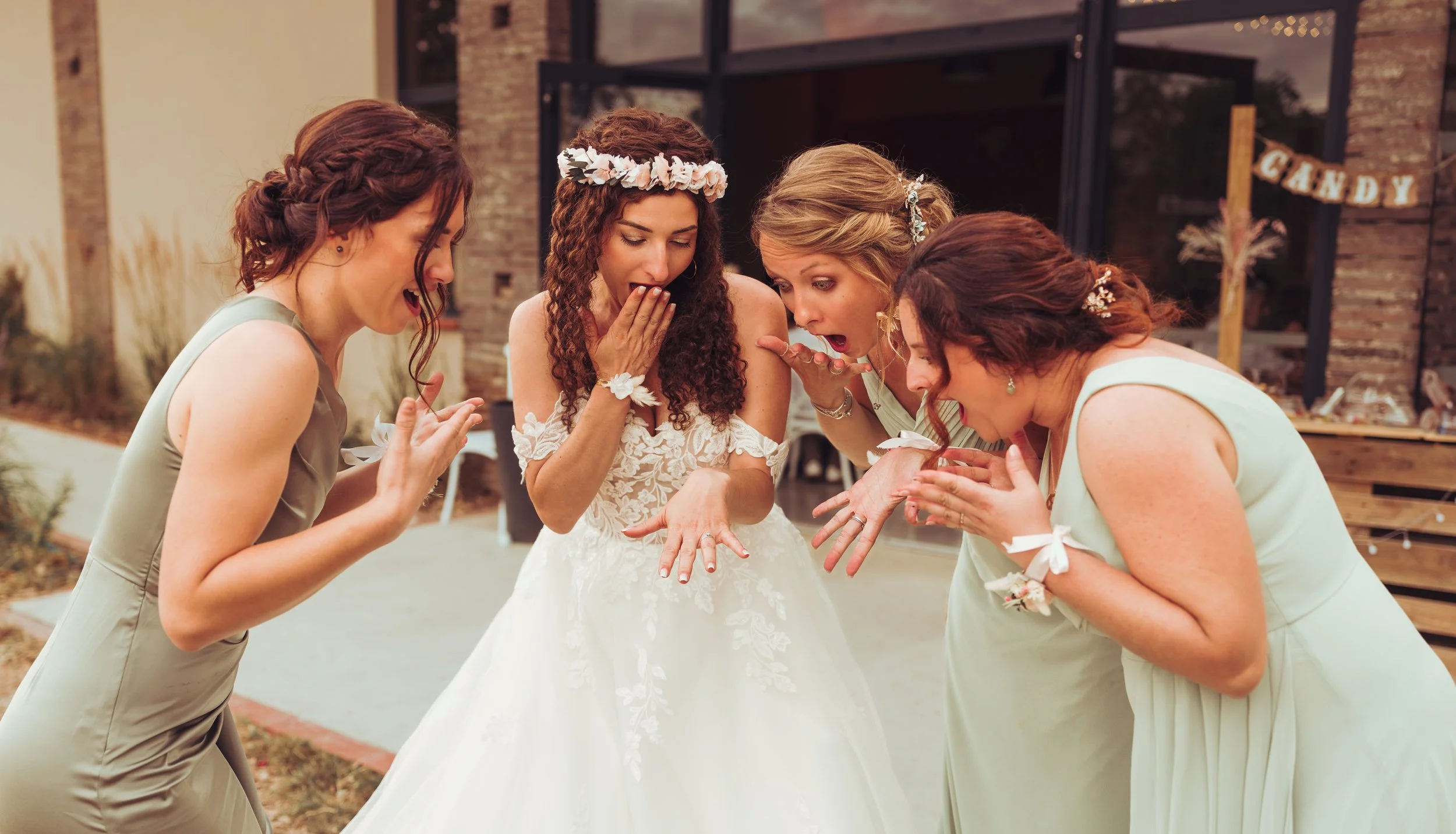Une mariée avec ses amies à la Métairie du Fusté qui découvrent ses mains avec des alliances lors d'une célébration de mariage en plein air.