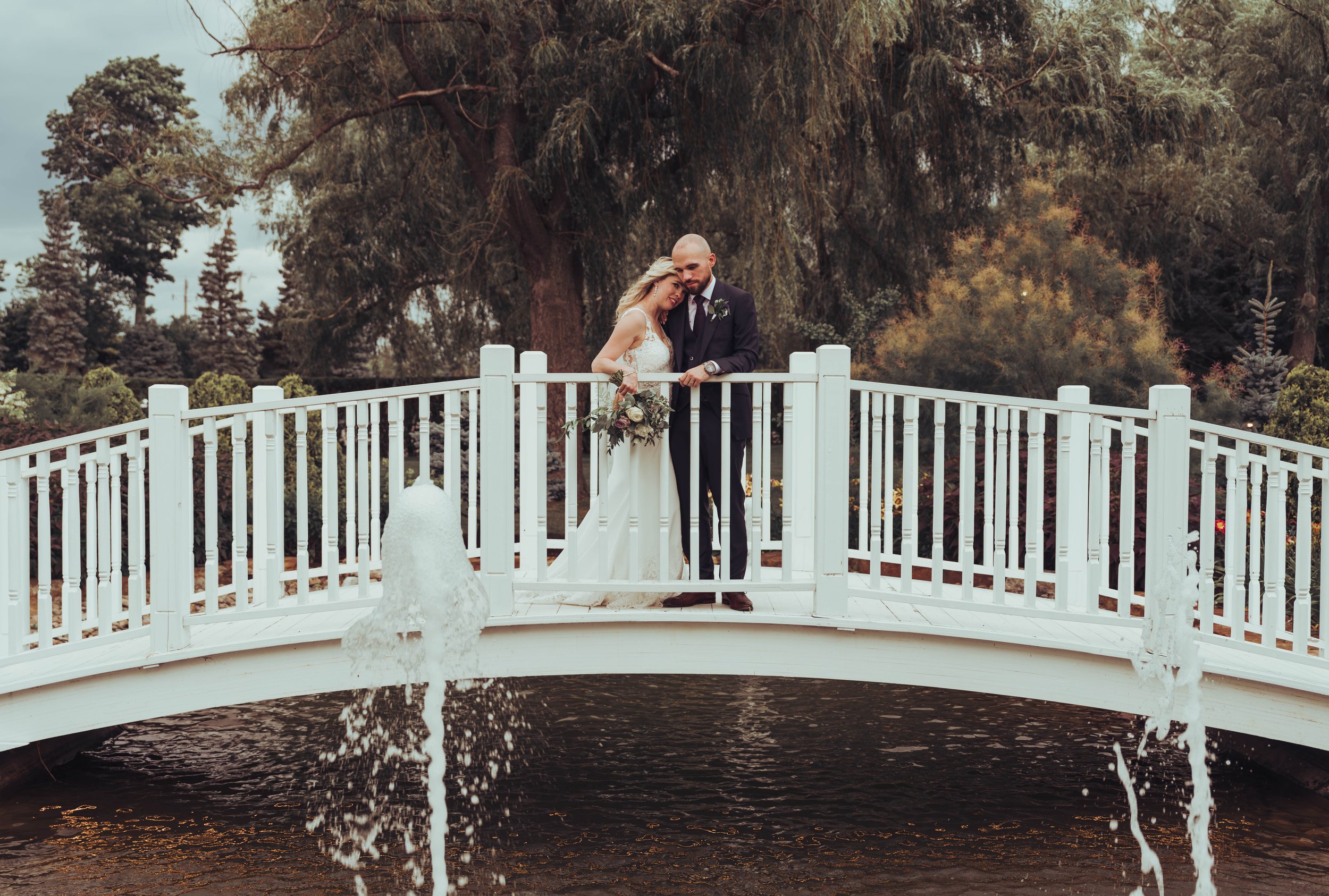 Un couple de mariés se tient sur un pont blanc au chateau Vaudreuil, Canada, le jour de leur mariage. 