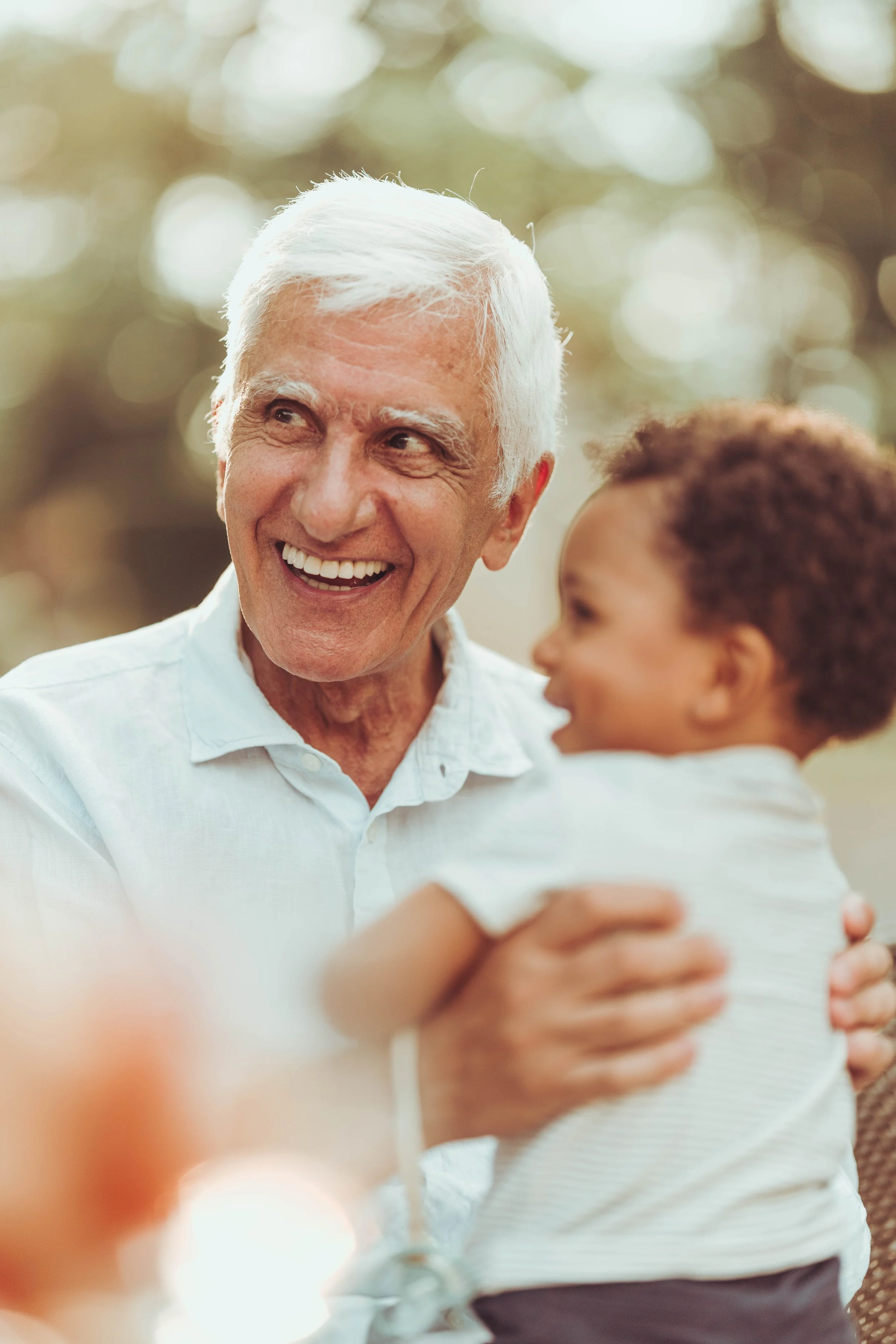 Un homme âgé souriant tenant son petit fils lors d'une fête de mariage au moulin de Rudelle, proche de Toulouse. 
