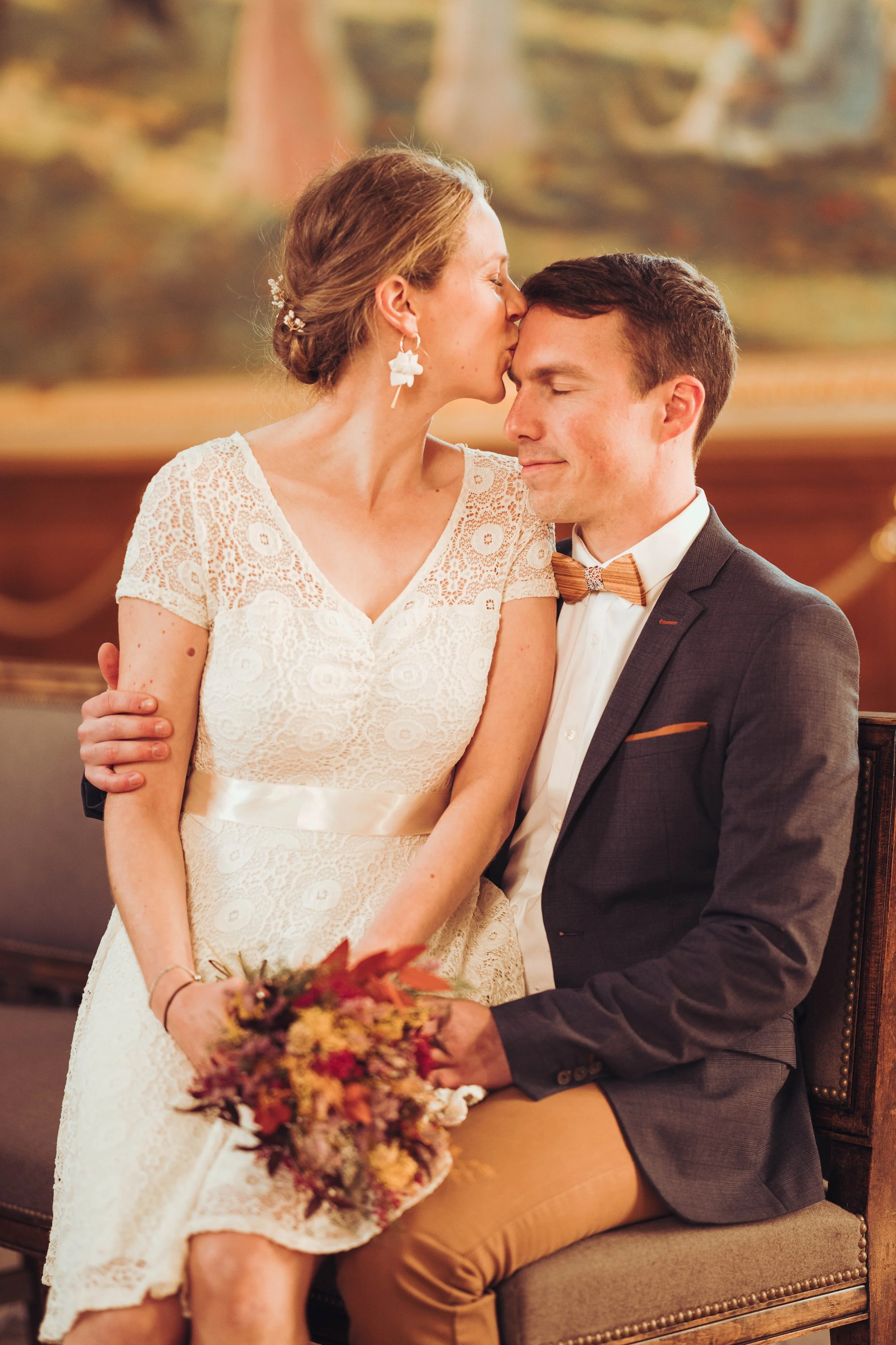 Une mariée embrasse tendrement son époux dans la salle des illustres du Capitole de Toulouse. 