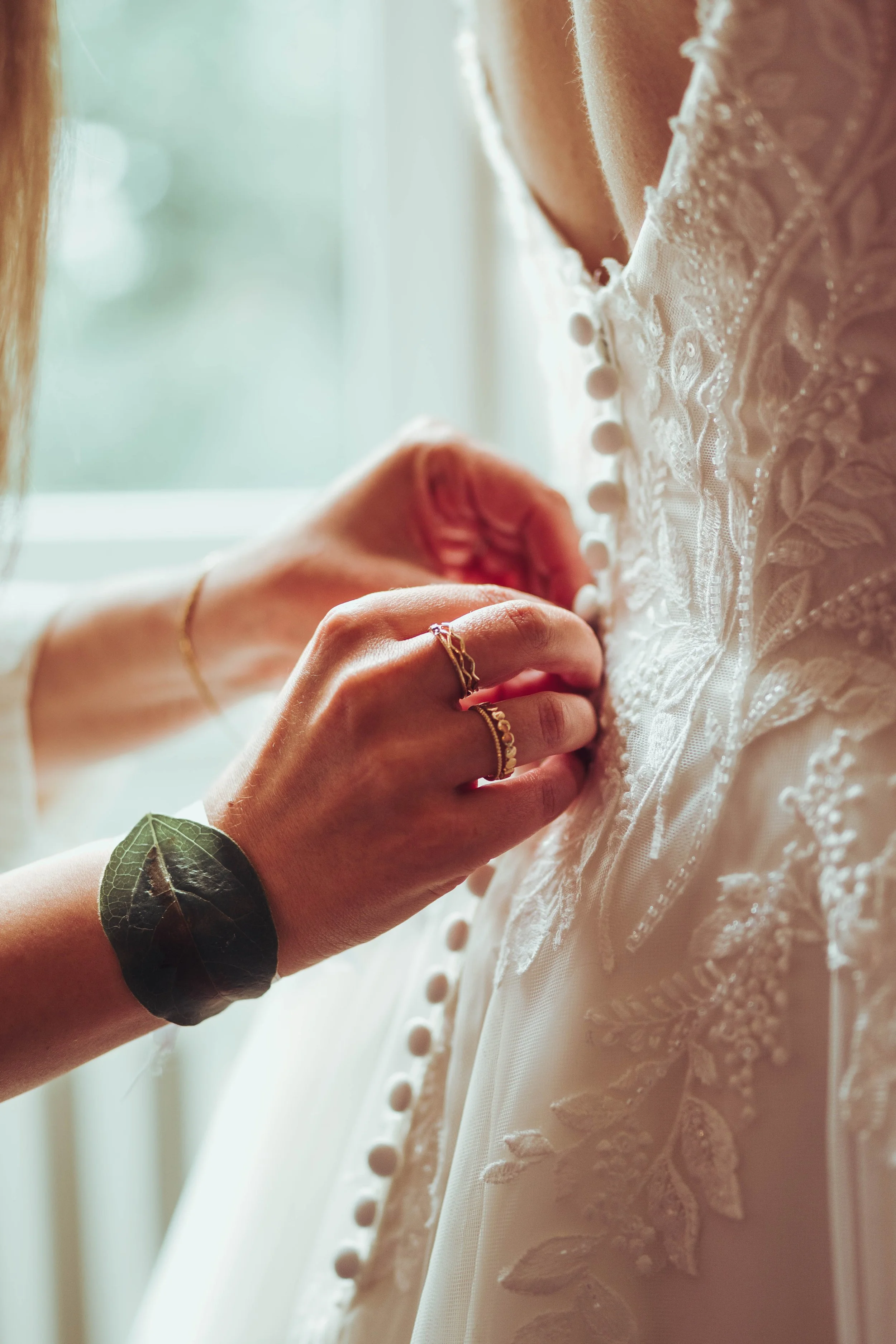 Une personne ajuste les boutons de la robe de mariée blanche avec des broderies florales et de la dentelle au château de Puydaniel près de Toulouse, en Occitanie. 