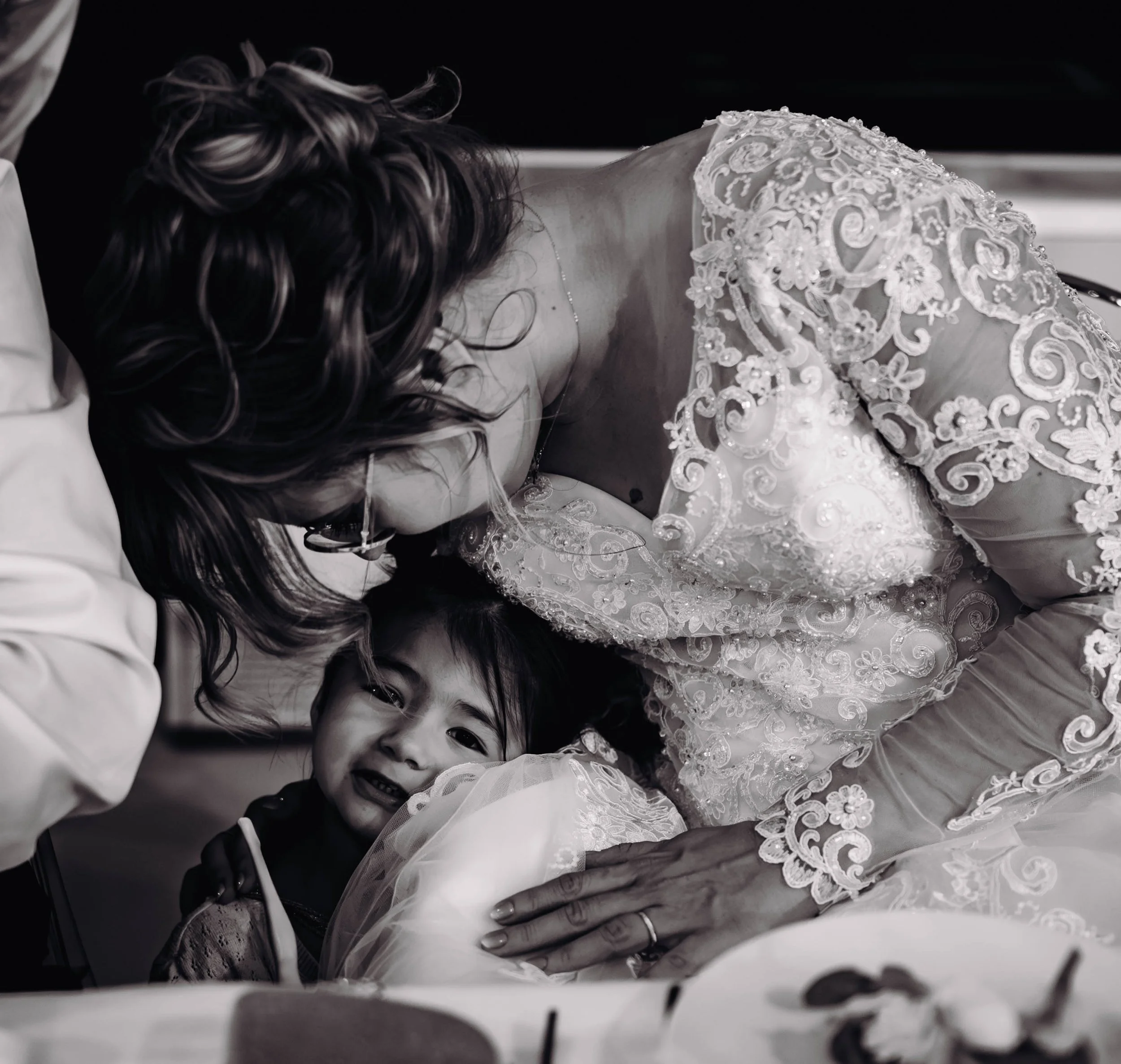 Une femme en robe de mariée pleure en serrant un enfant dans ses bras dans une scène émotive en noir et blanc proche de Toulouse.