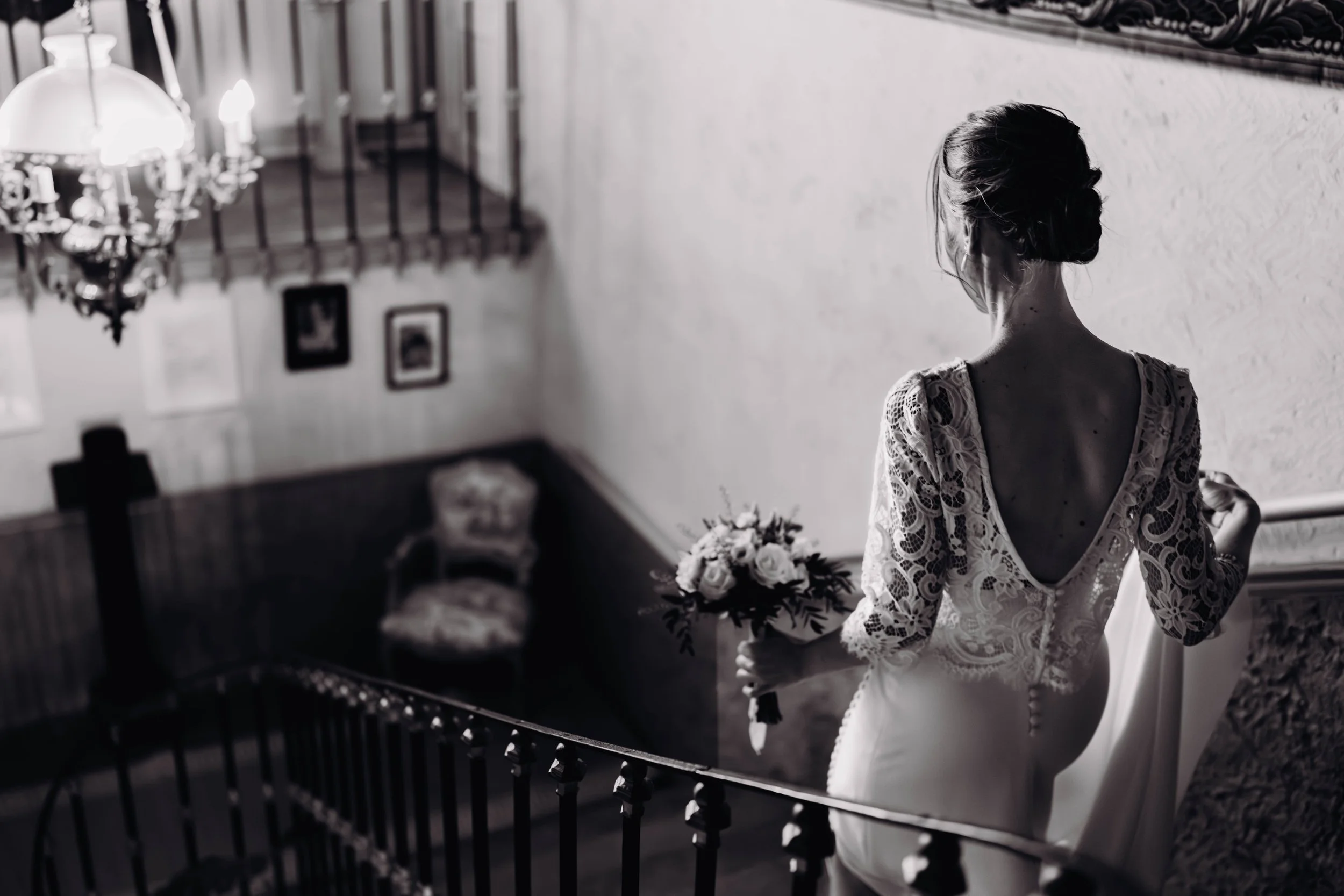 Une femme en robe de mariée vue de dos, descend l'escalier du Manoir de Lisle (dans le Tarn, proche de Toulouse) tenant un bouquet de fleurs. Elle se dirige vers son futur époux pour réaliser leur first look. 