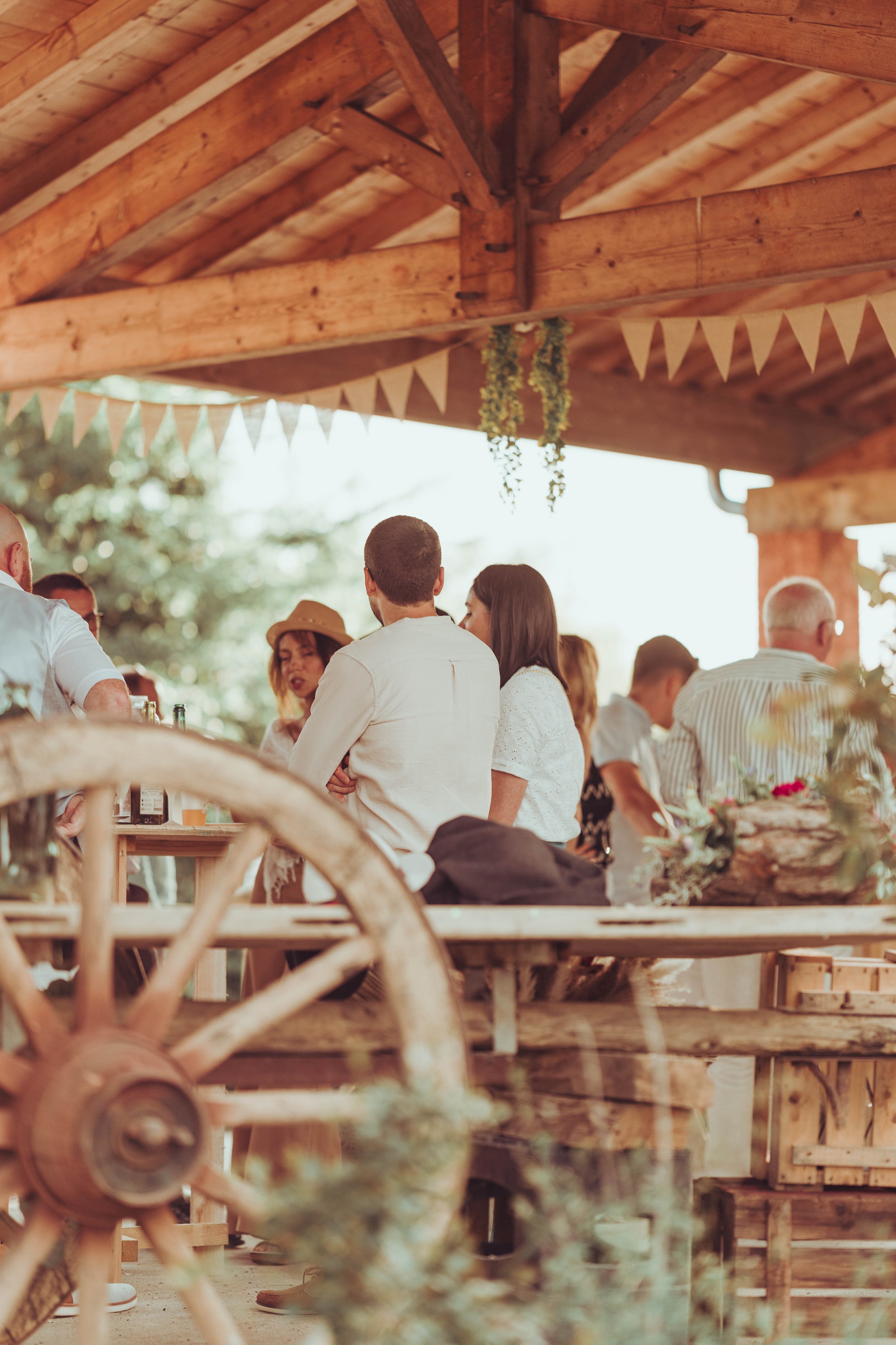Groupe de personnes réunies lors d'une fête de mariage proche de Toulouse, sous un toit en bois, décoré de guirlandes de fanions, en plein air