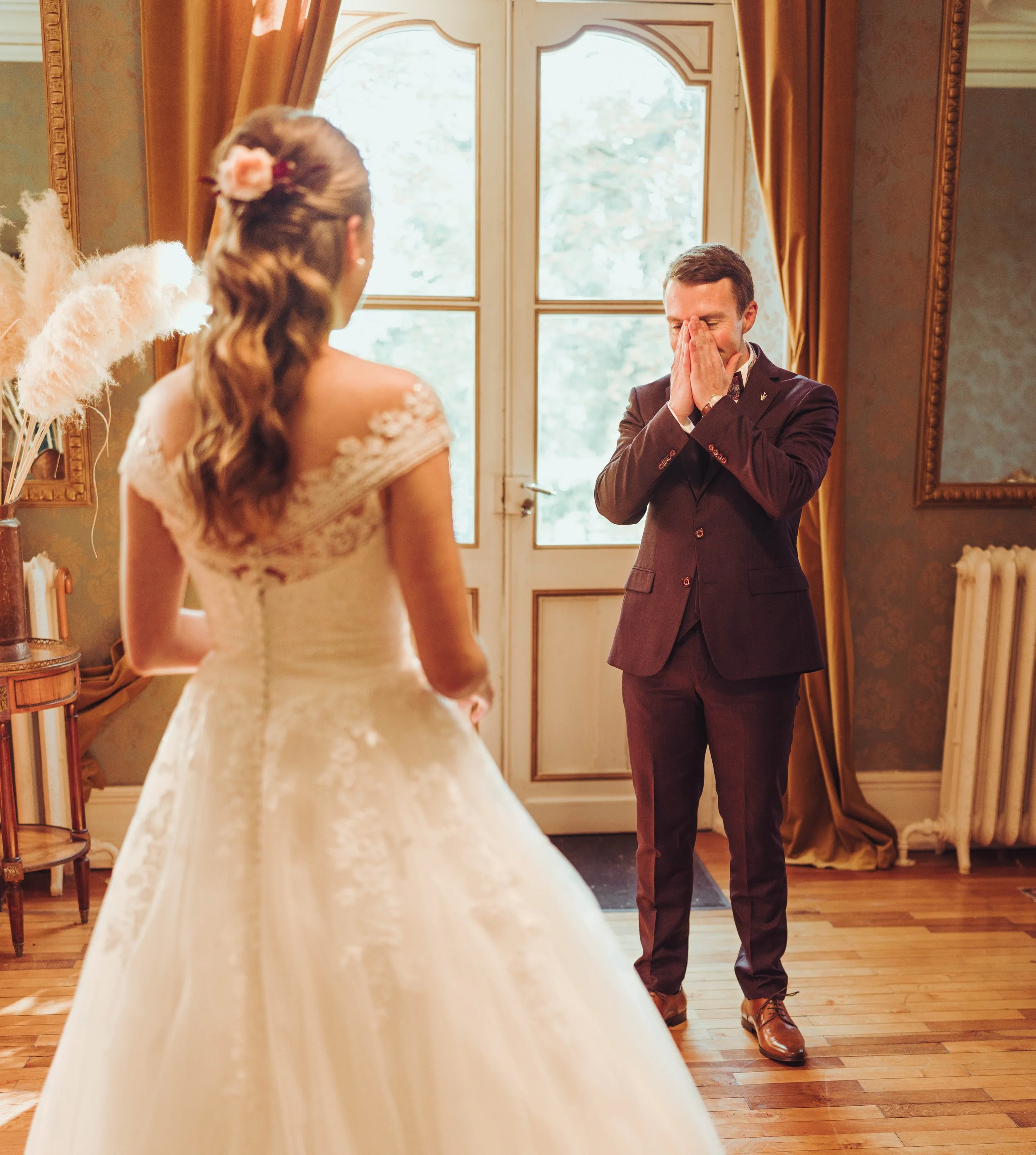 Un couple de mariés se voit pour la première fois leur leur first look au manoir du Thouron, l'homme semble très ému, couvrant son visage avec ses mains, tandis que la femme en robe de mariage regarde le marié.