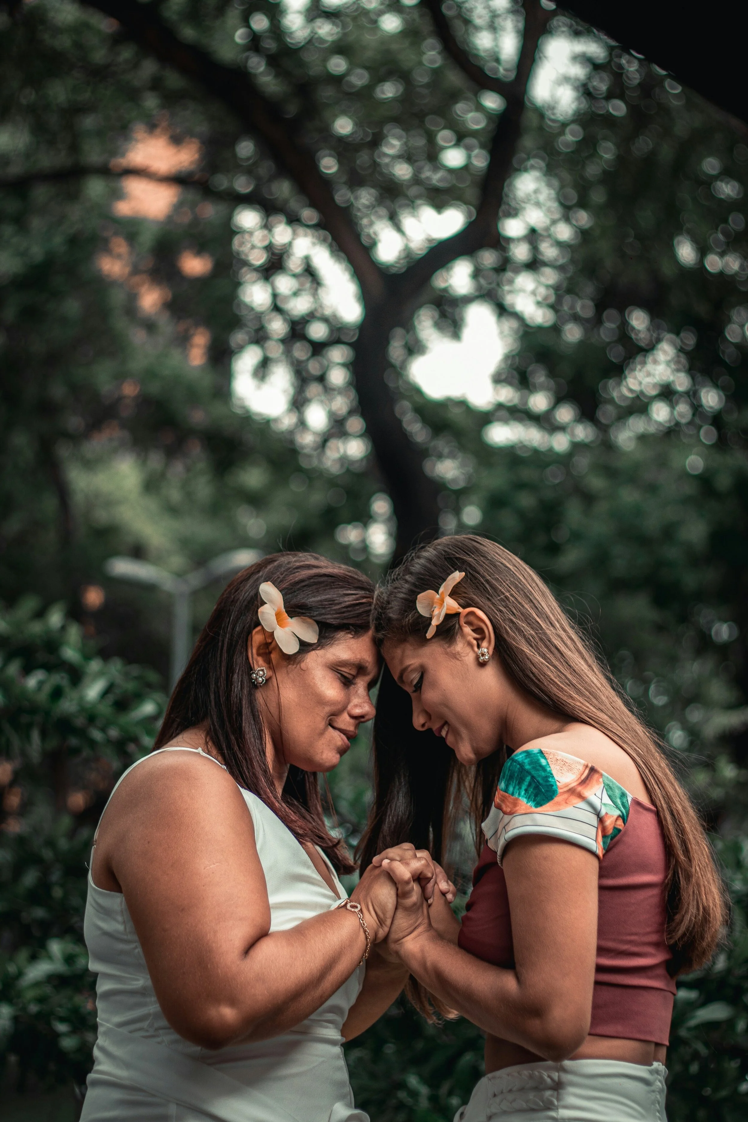 Two women holding hands with foreheads touching representative of healing relationship wounds