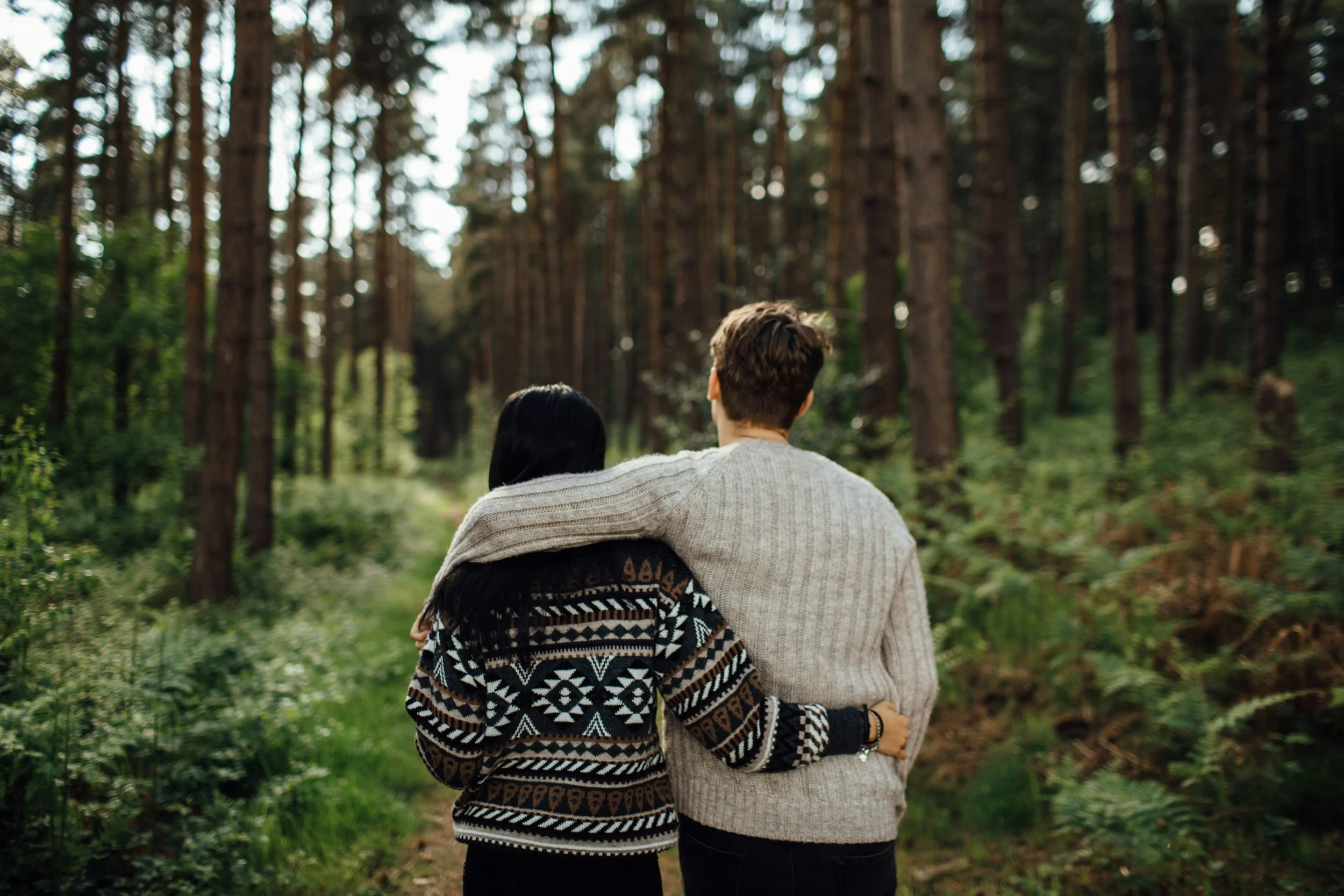 Couple walking arm in arm through a pine forest representative of healing together